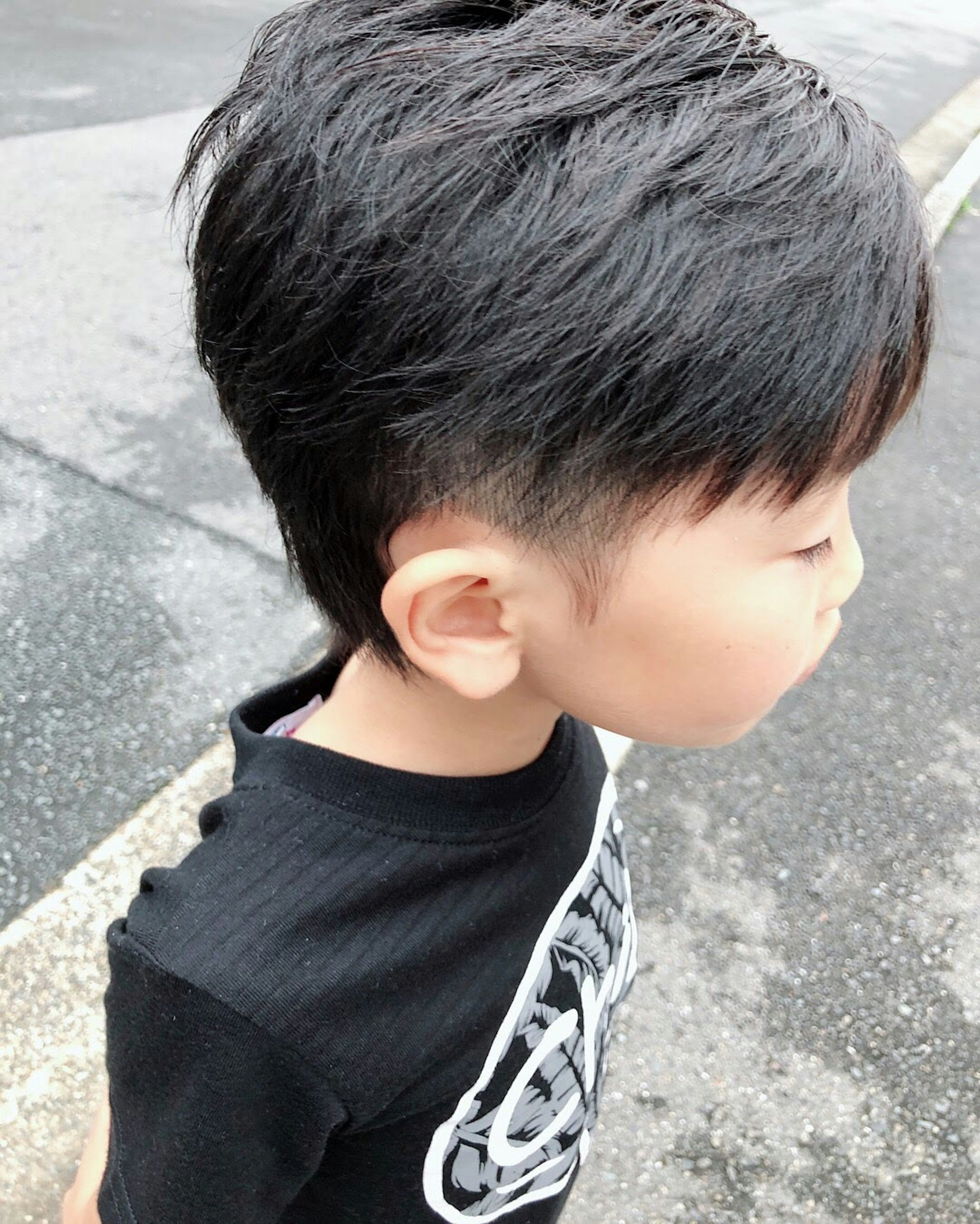 Seorang anak laki-laki dengan gaya rambut pendek melihat ke samping