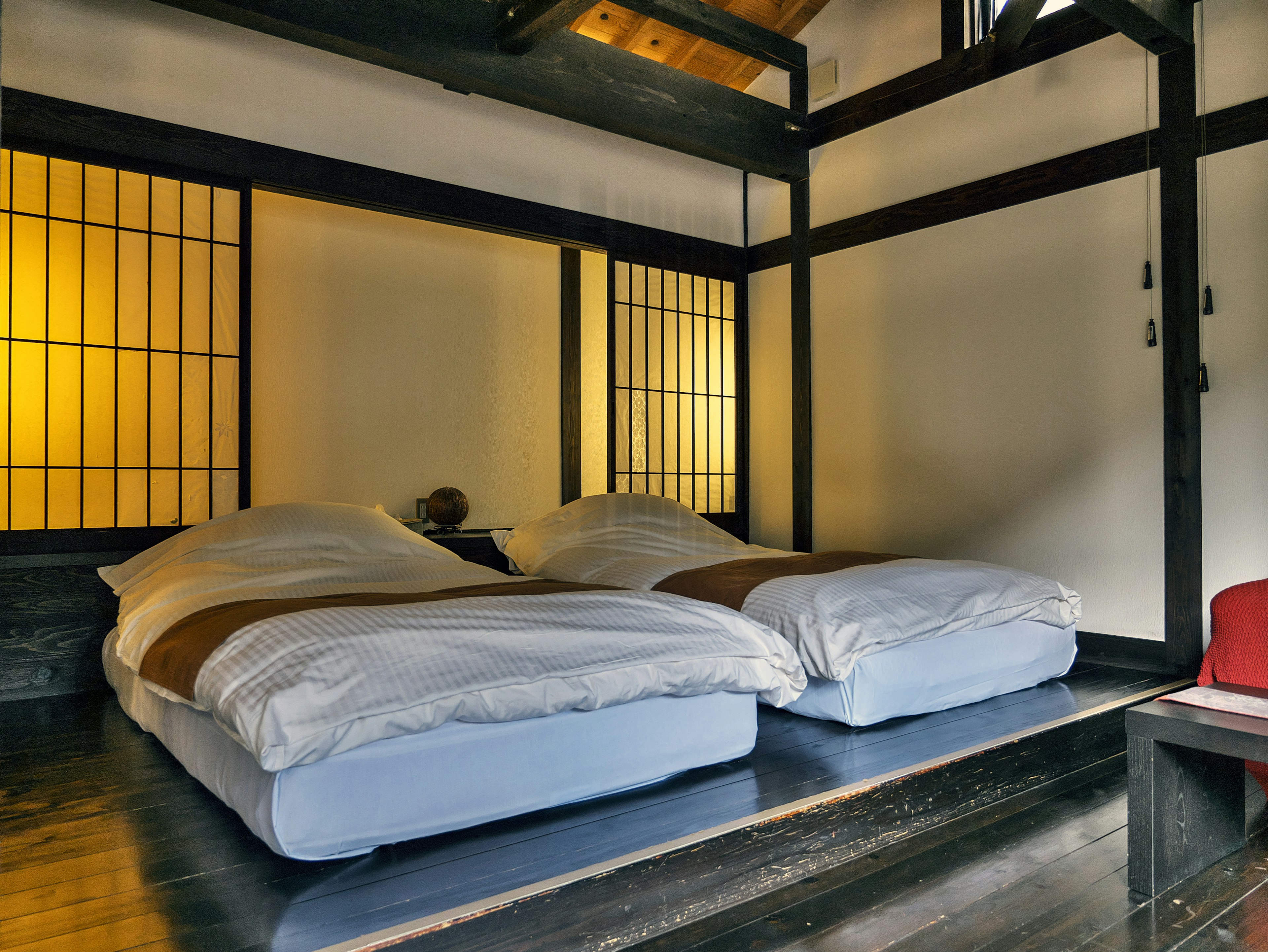 Minimalistisches Schlafzimmer mit zwei Betten im traditionellen japanischen Stil und sanfter Beleuchtung