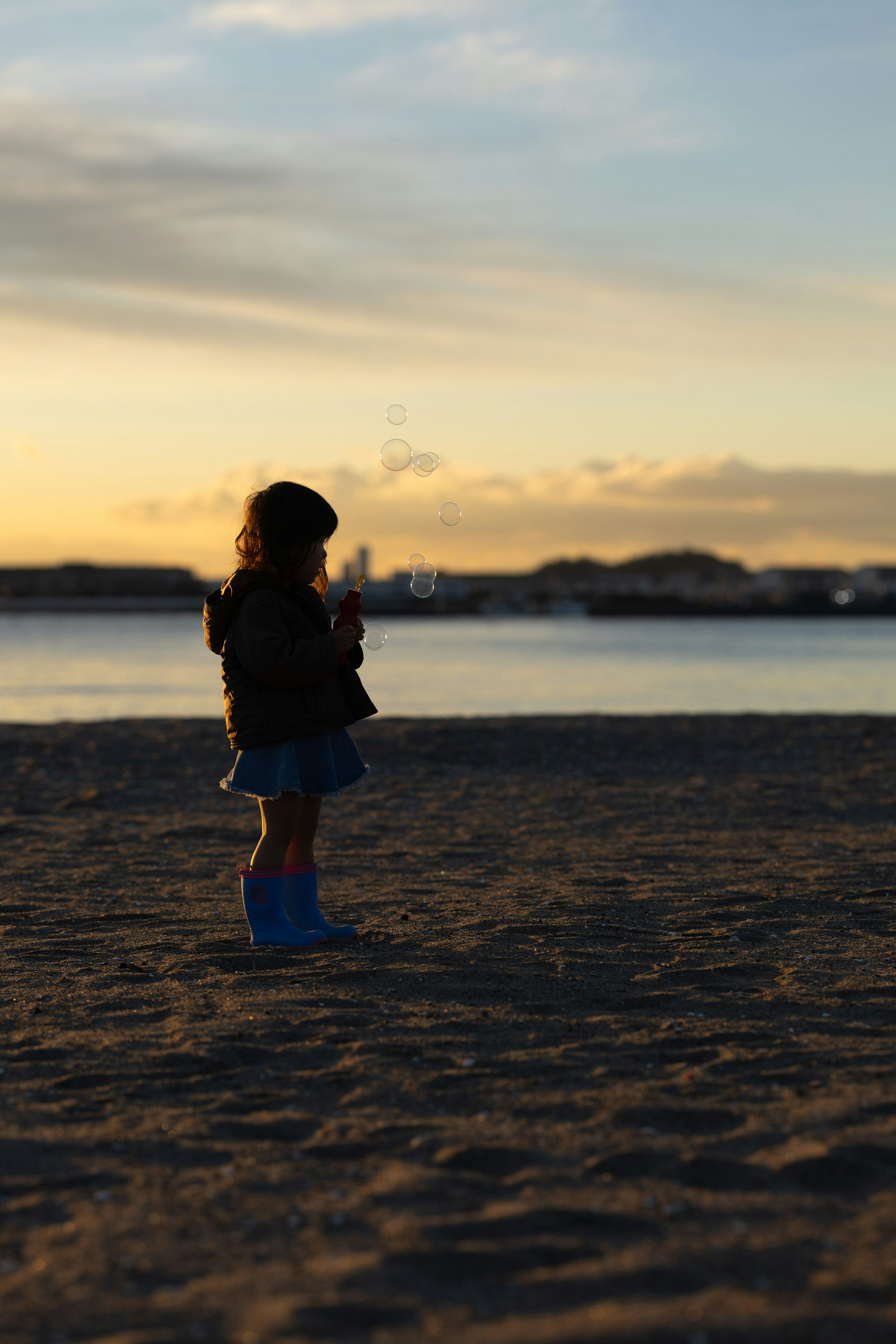 夕暮れ時の砂浜に立つ子供のシルエット