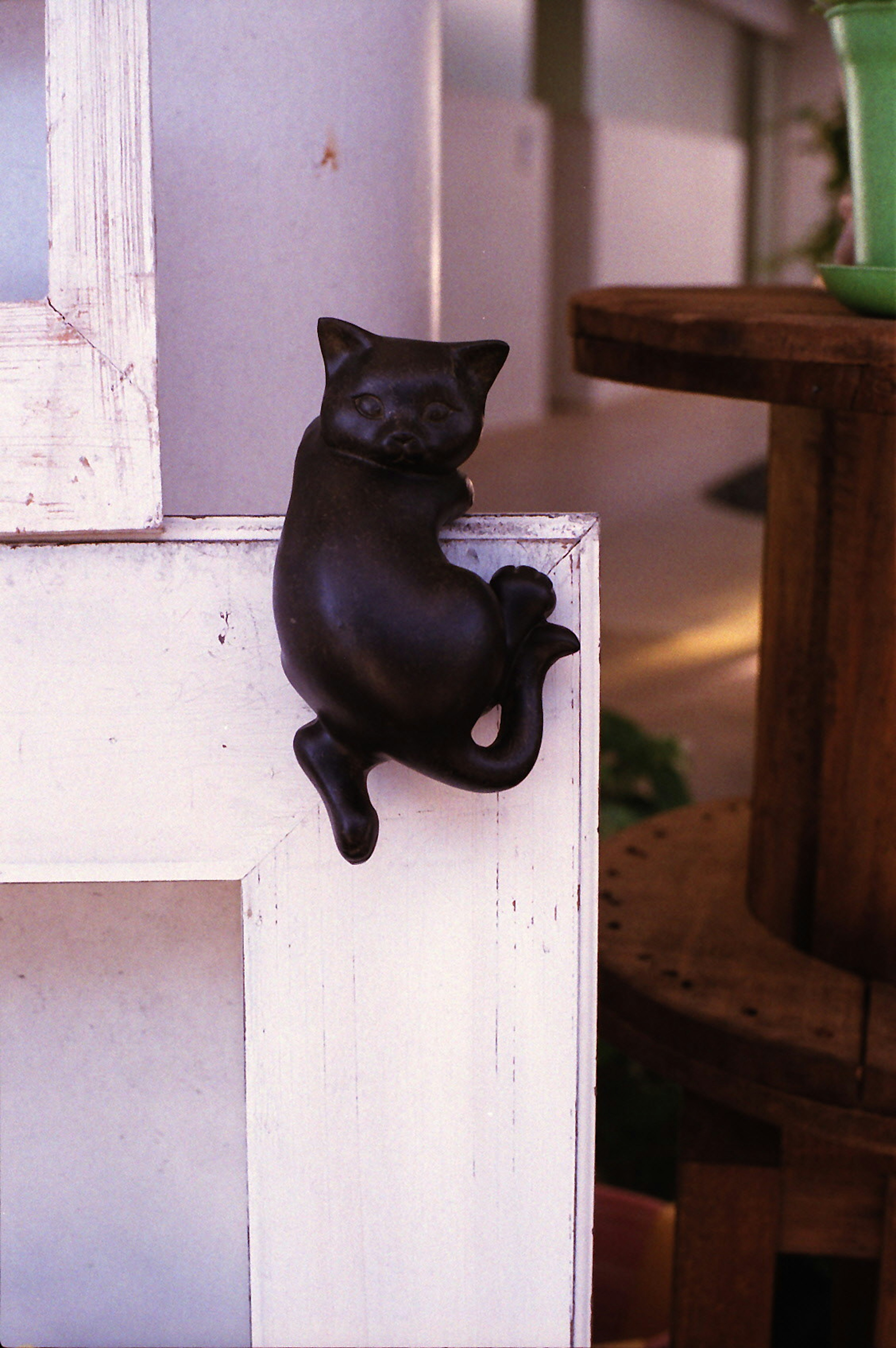 A black cat sculpture leaning against a white frame