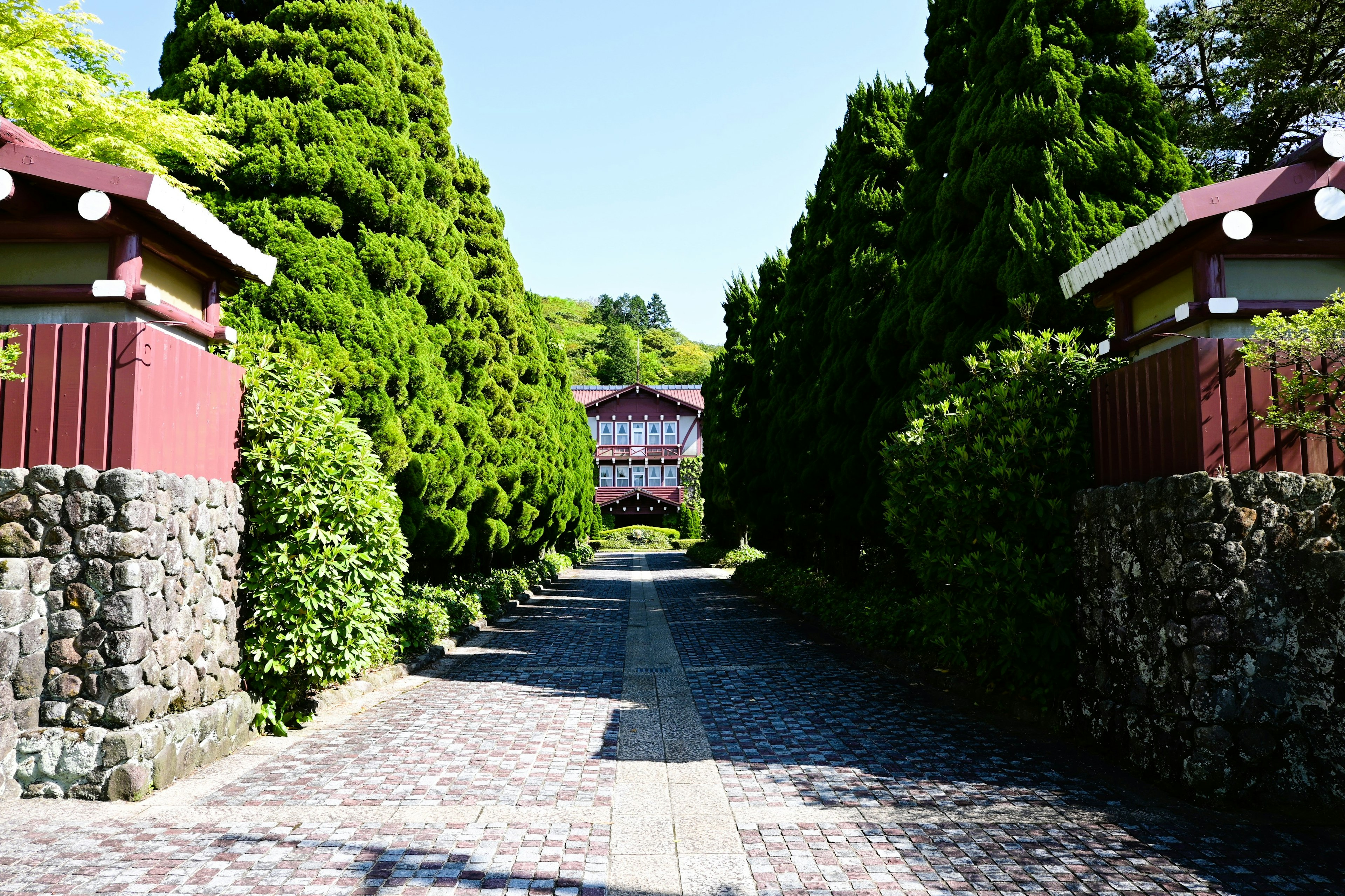 Un chemin pavé de pierres bordé de verdure menant à un bâtiment japonais traditionnel