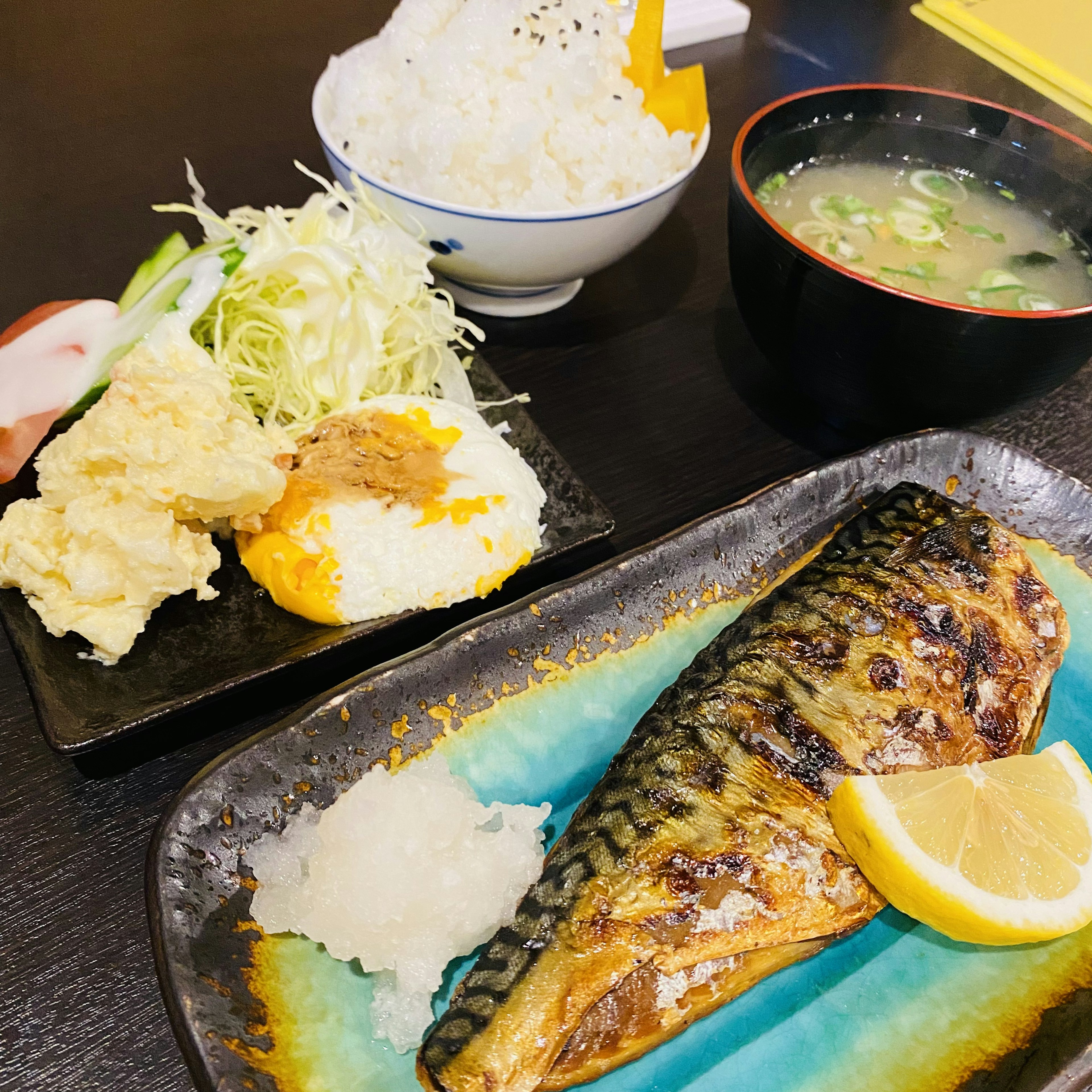 焼き魚とご飯のセット 魚にレモンのスライスと大根おろし 付け合わせにサラダと天ぷら