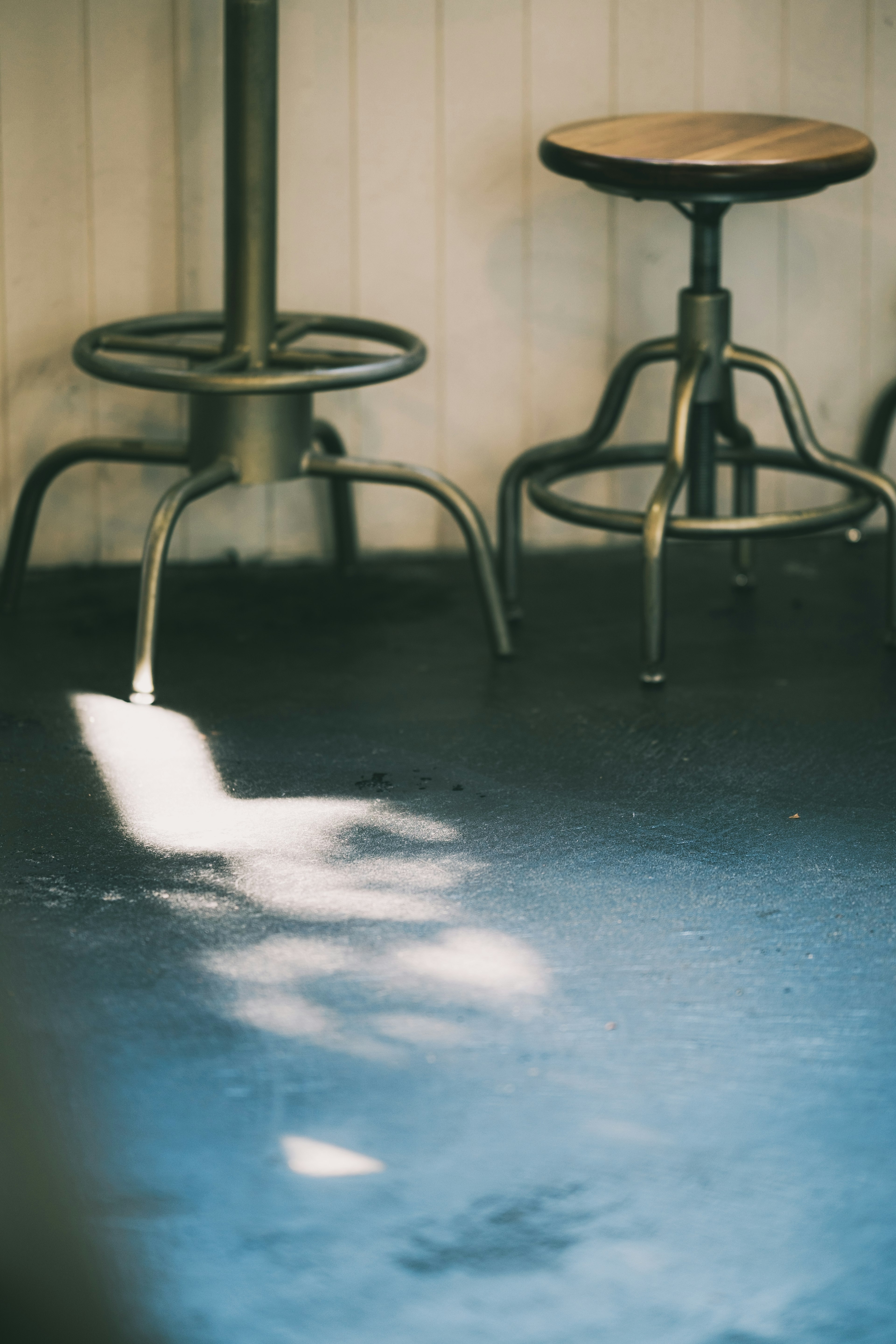 Intérieur d'un café avec des reflets de lumière sur le sol et un tabouret