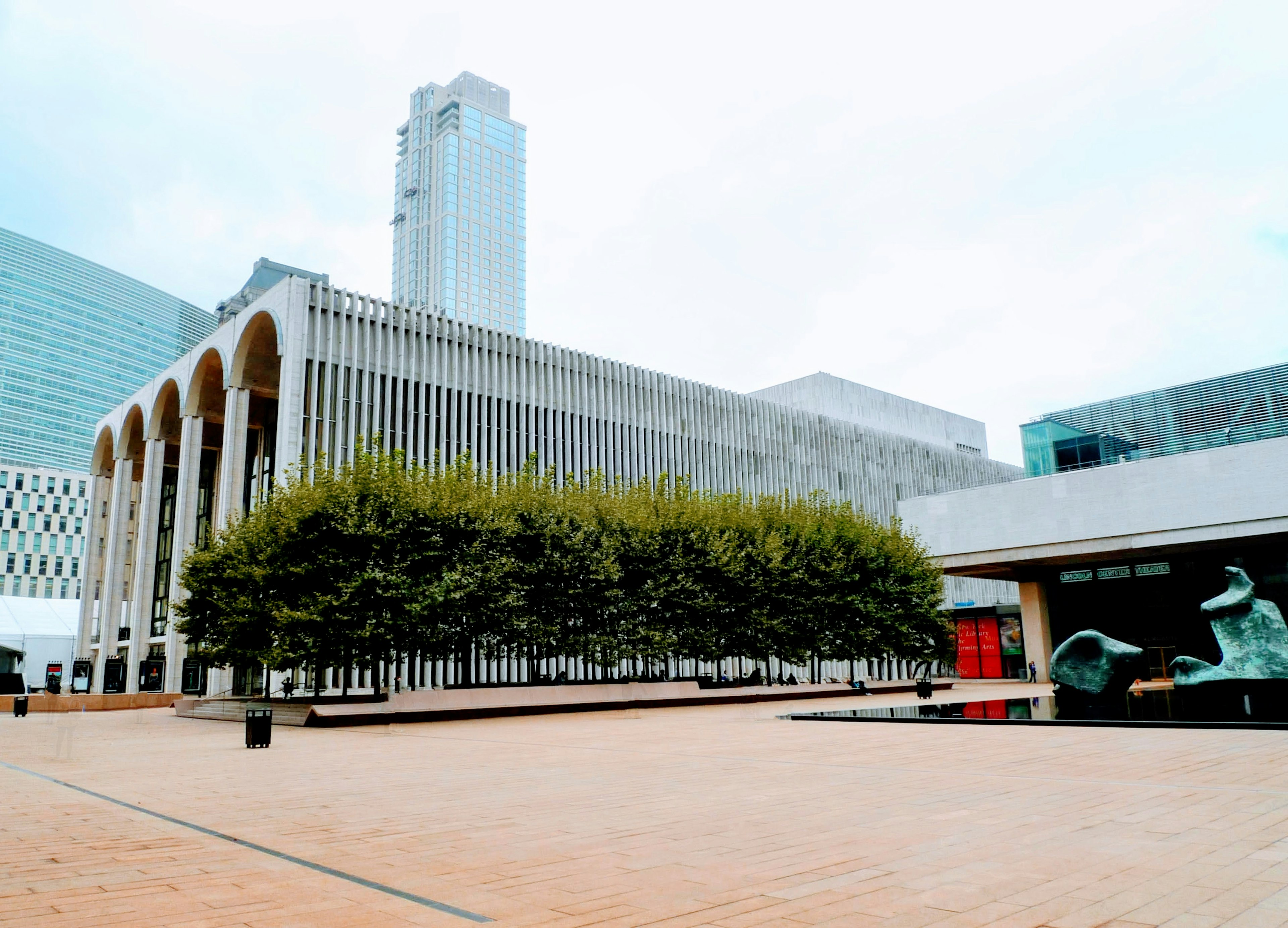 Bangunan modern dengan pohon hijau subur di plaza terbuka