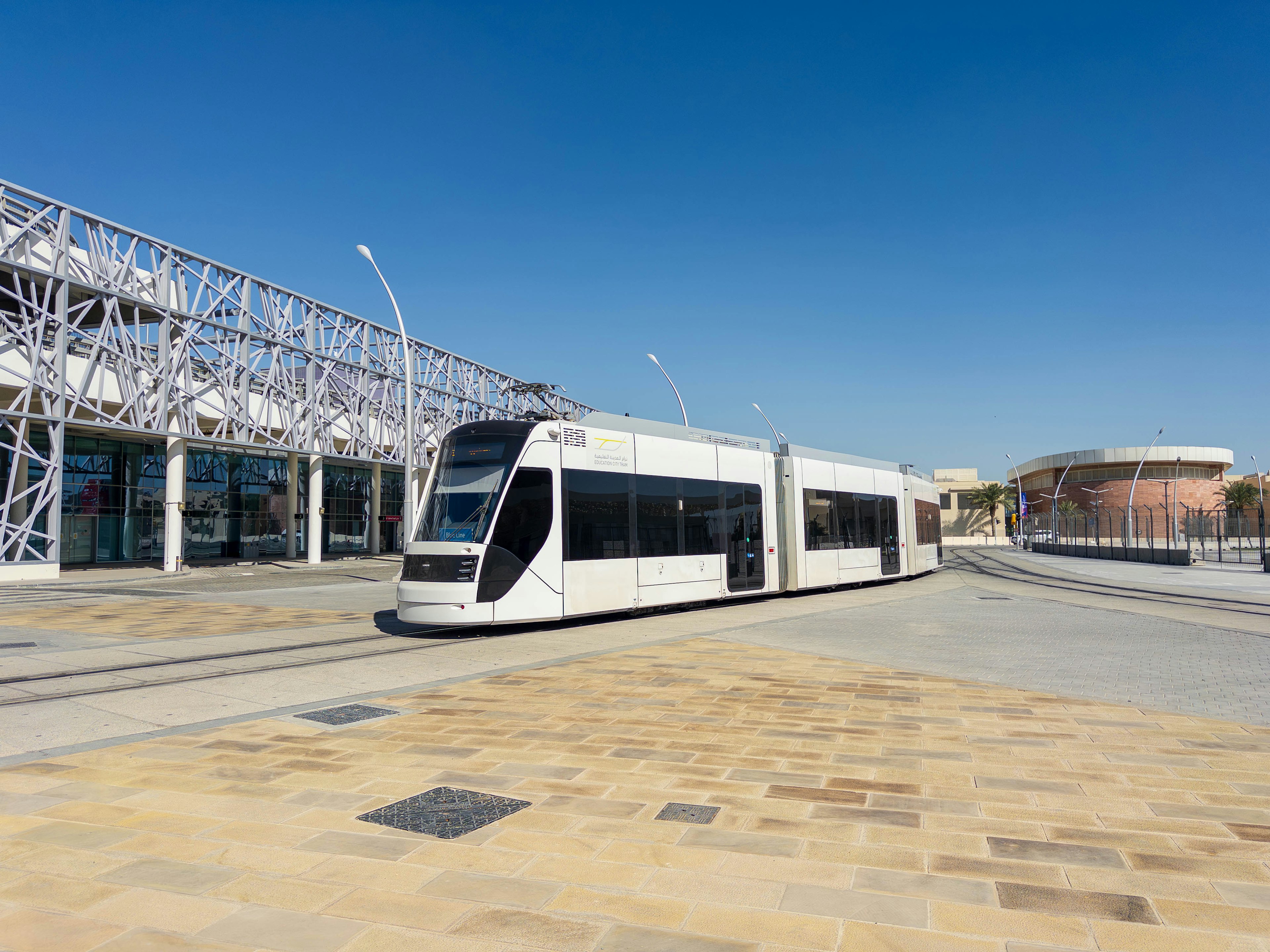 Un tram bianco in una piazza moderna con architettura contemporanea