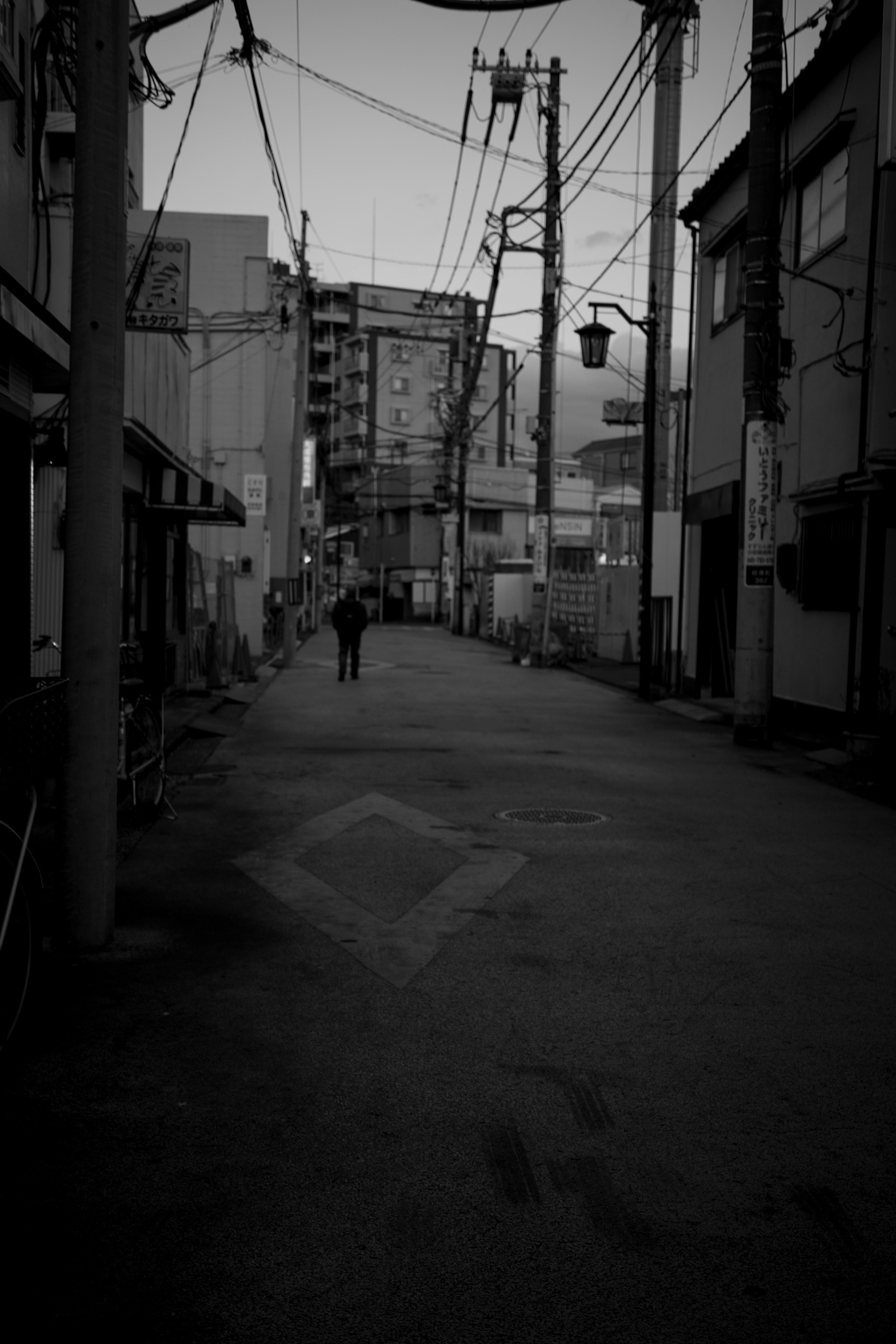 暗い路地に立つ人影と電線の景色