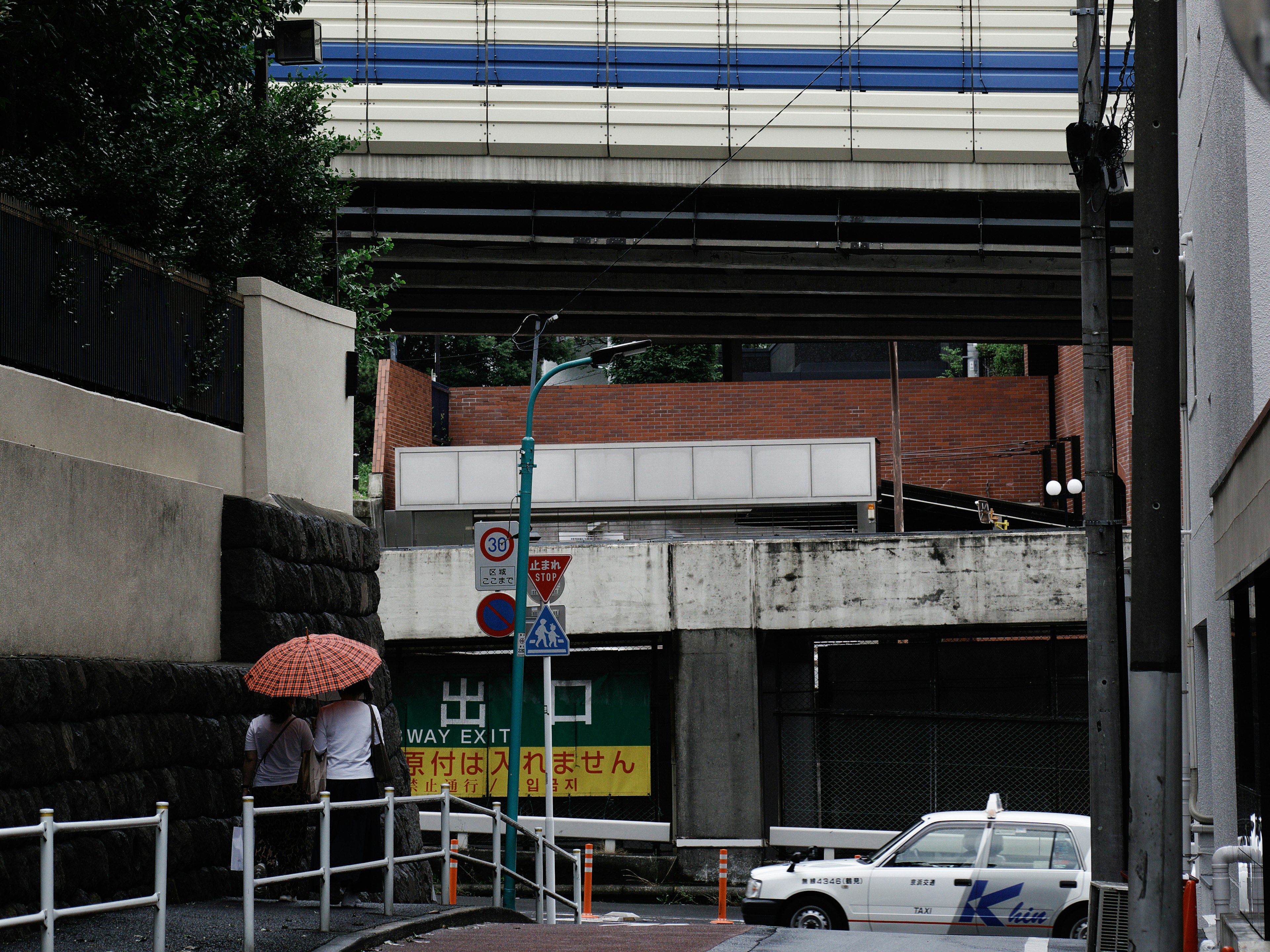 街道場景，出租車和傘下的人們靠近高架橋