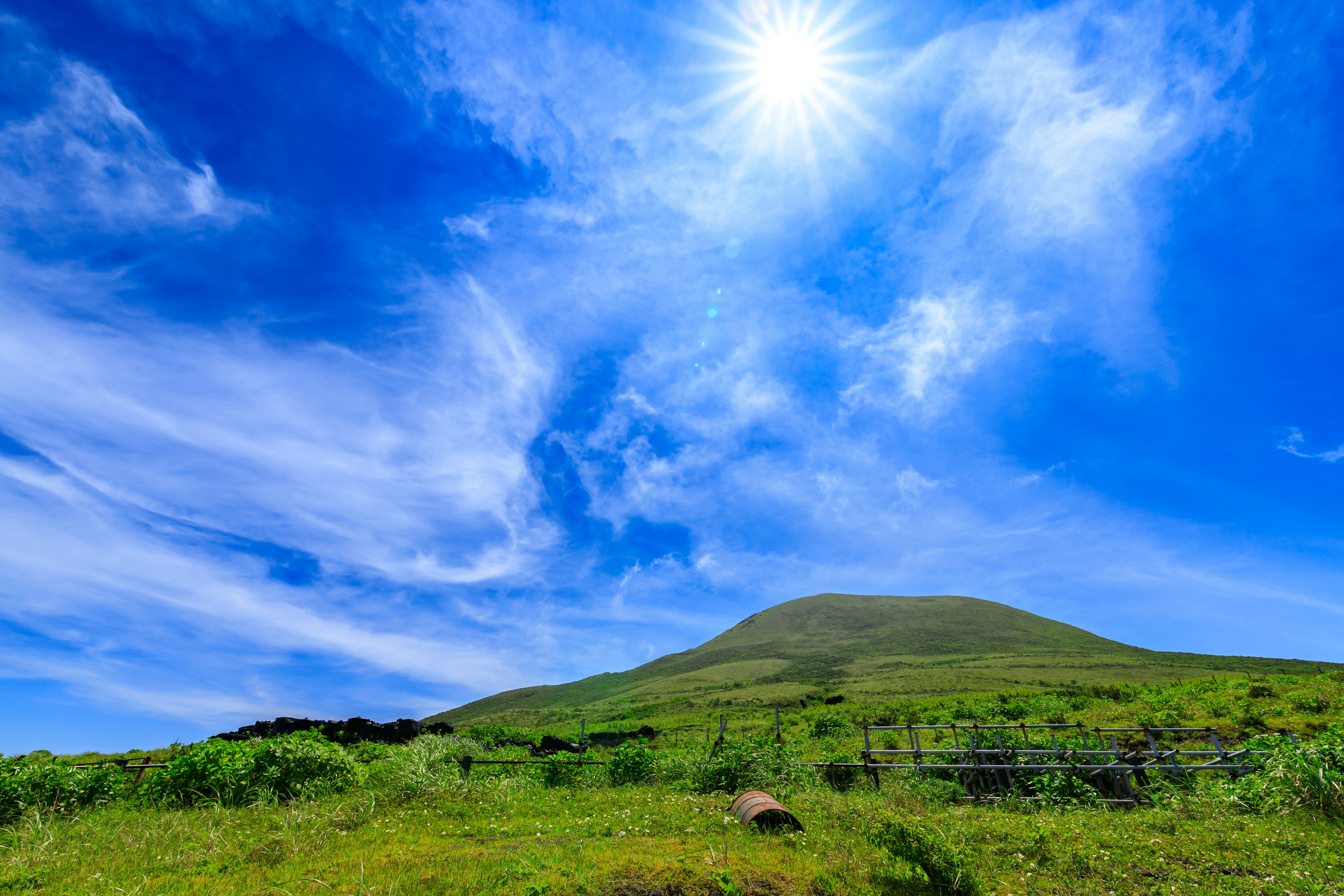 Colina verde bajo un cielo azul brillante y sol