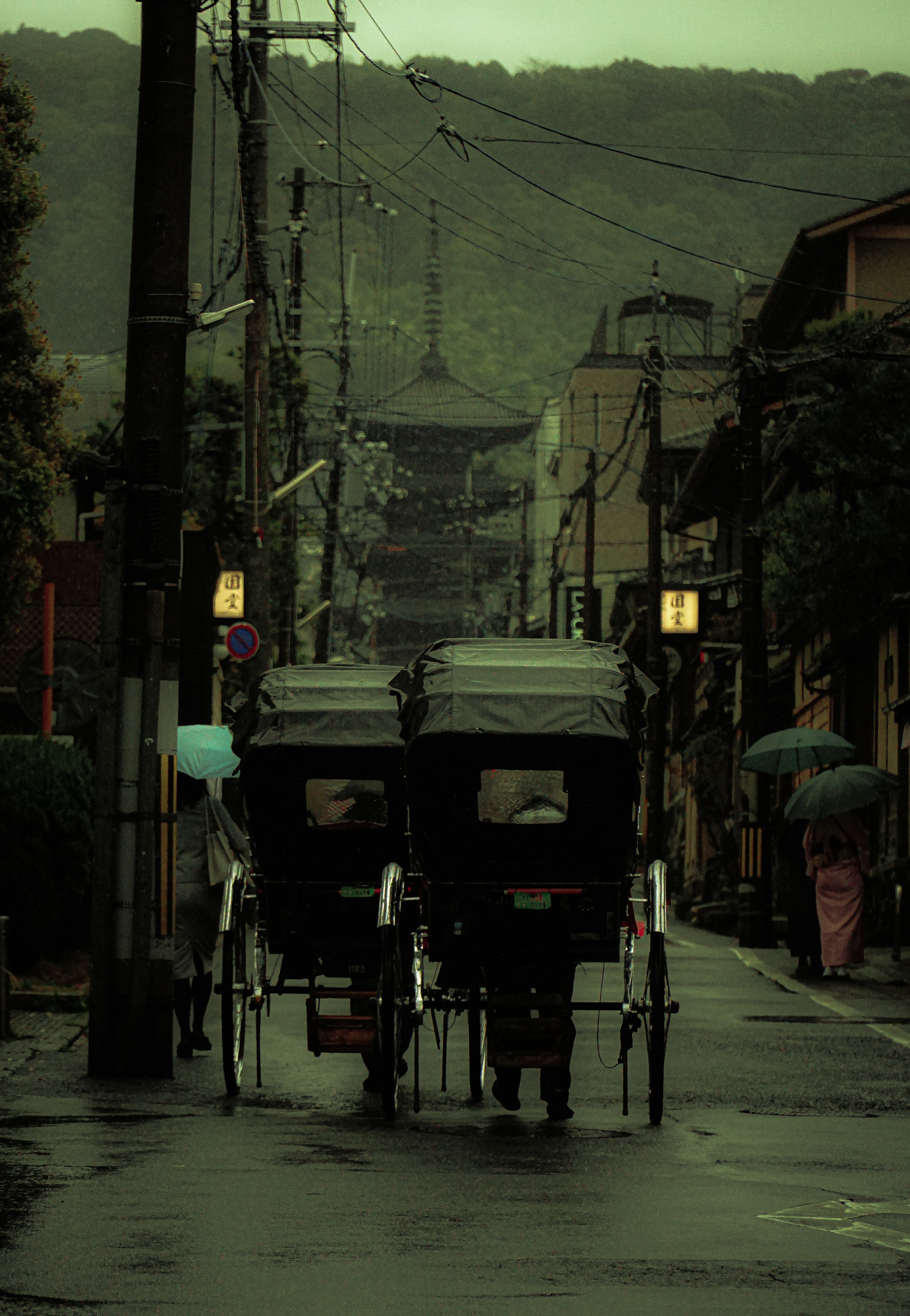 雨の中の人力車と古い街並みの風景