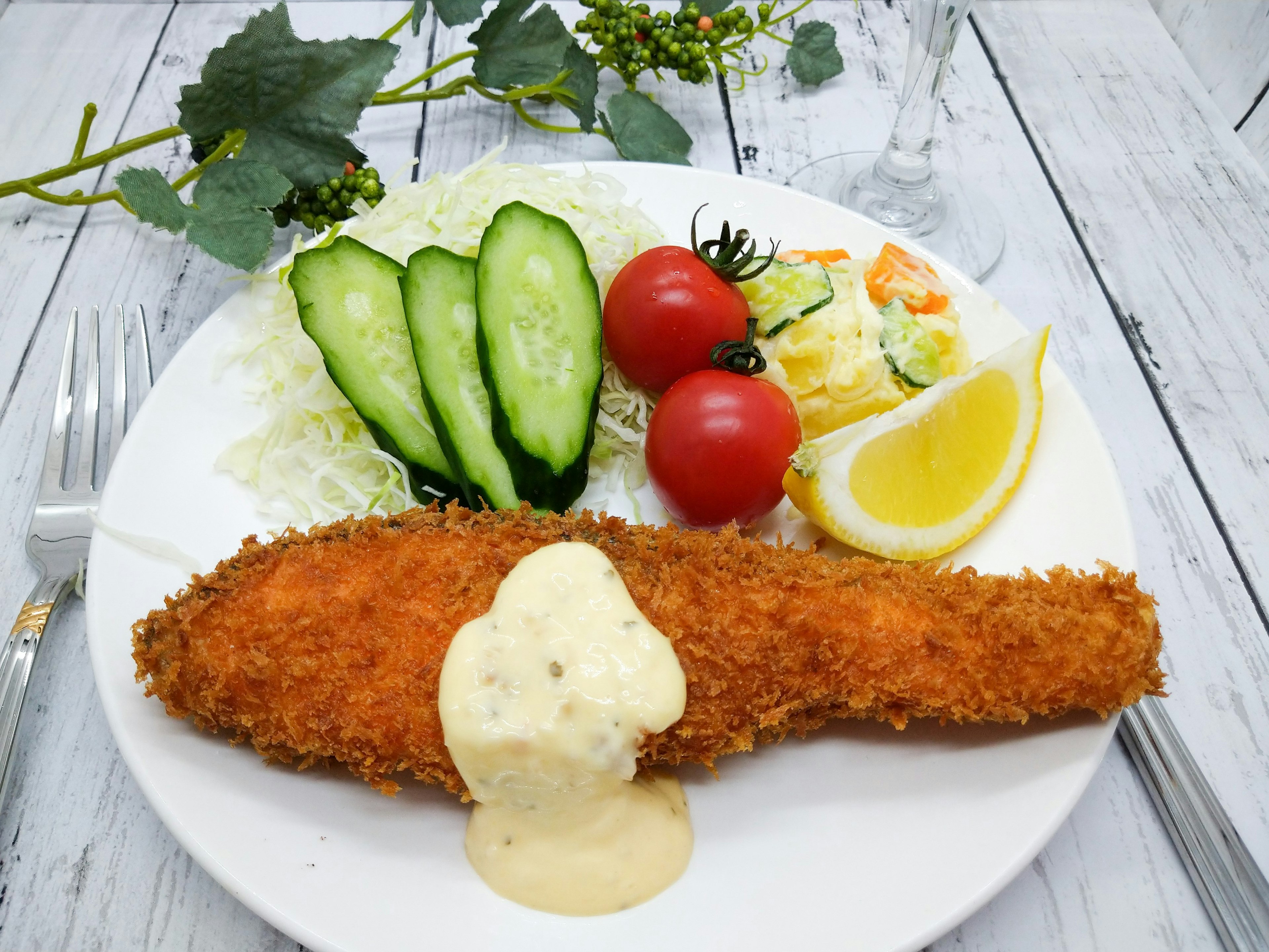 Poisson frit croustillant avec sauce crémeuse et tranches de citron accompagné de concombres et de tomates cerises