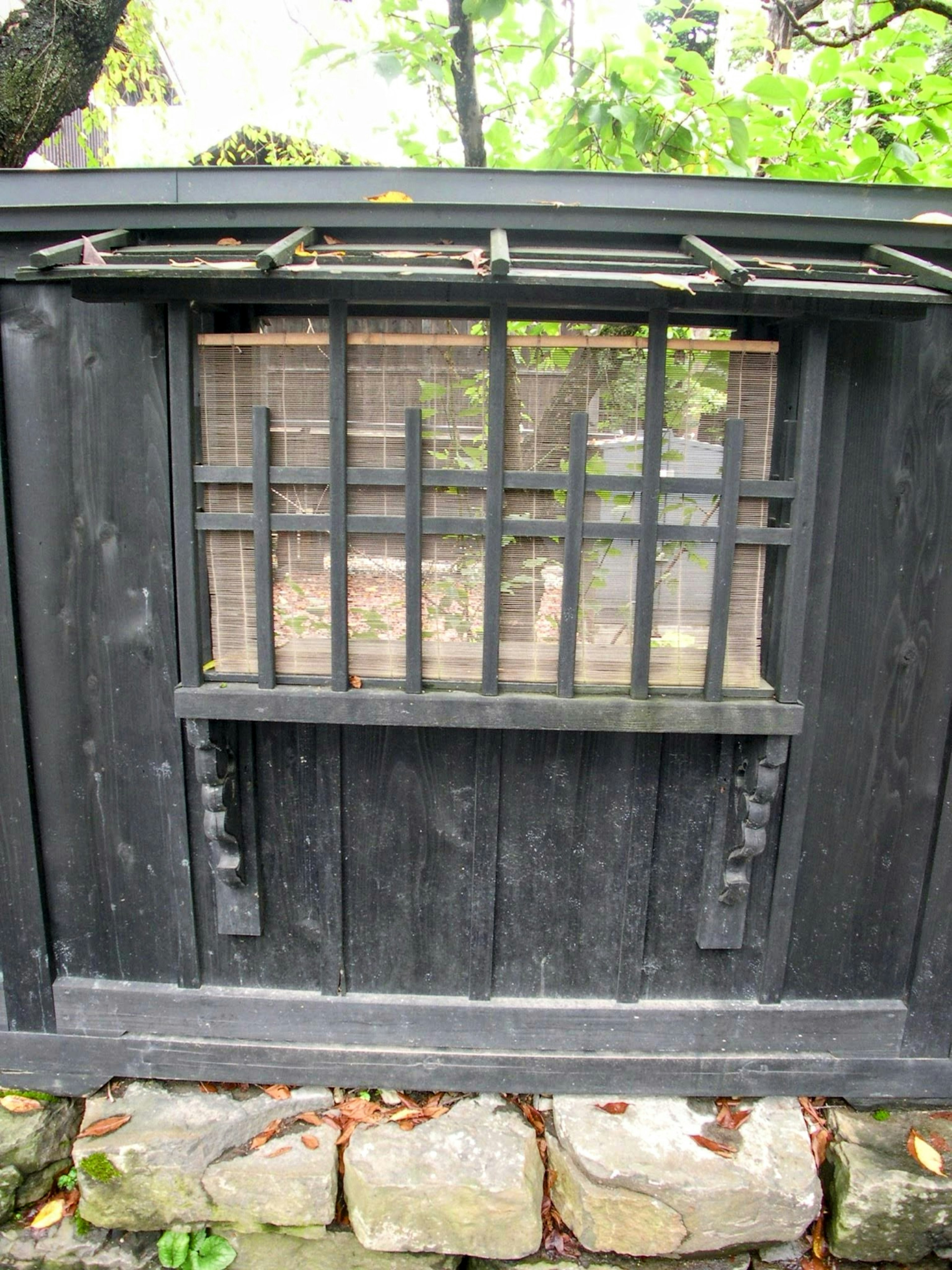 Merkmal eines traditionellen japanischen Hauses mit schwarzen Holzfenstergittern und Steinfundament