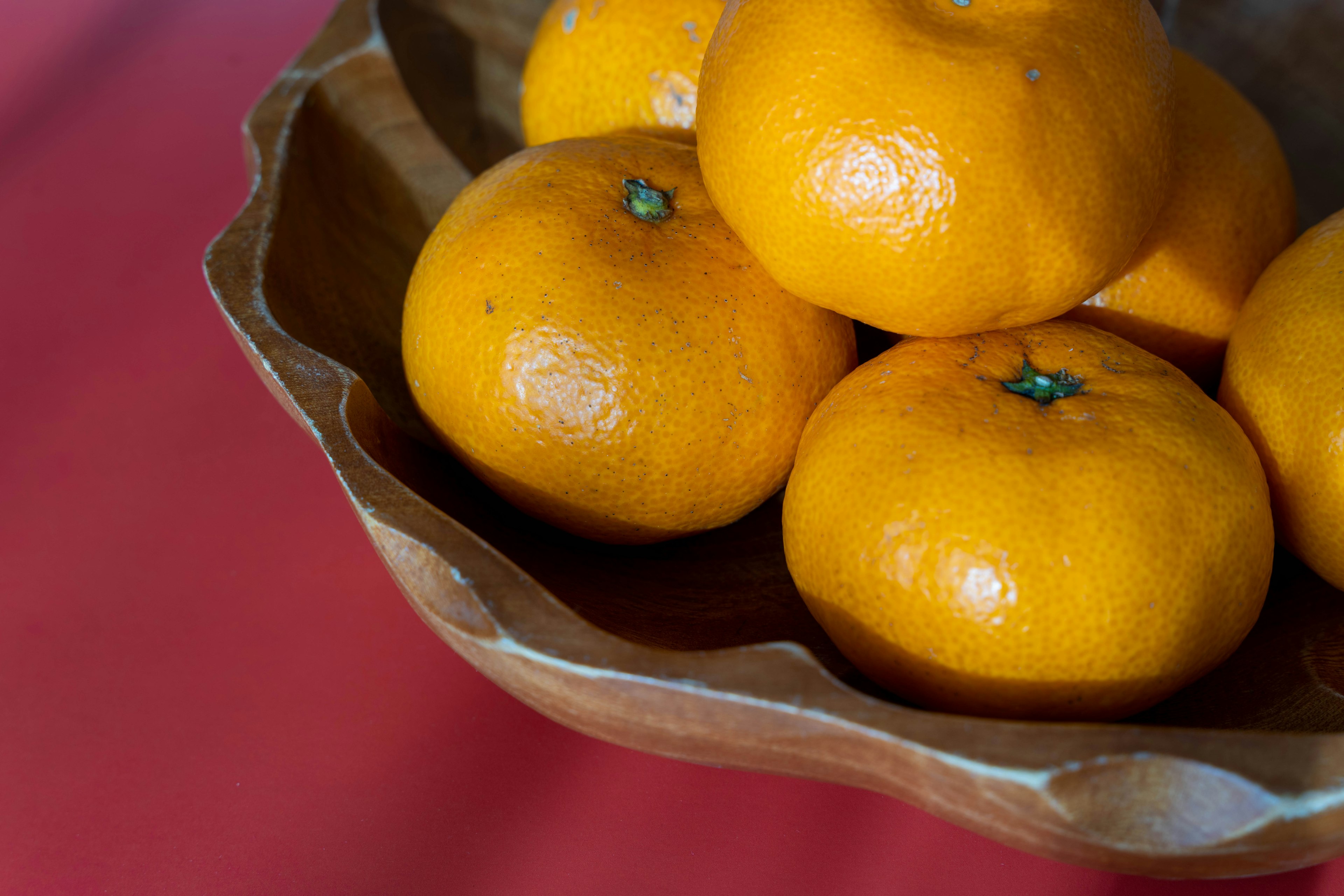 Jeruk mandarin oranye cerah dalam mangkuk kayu