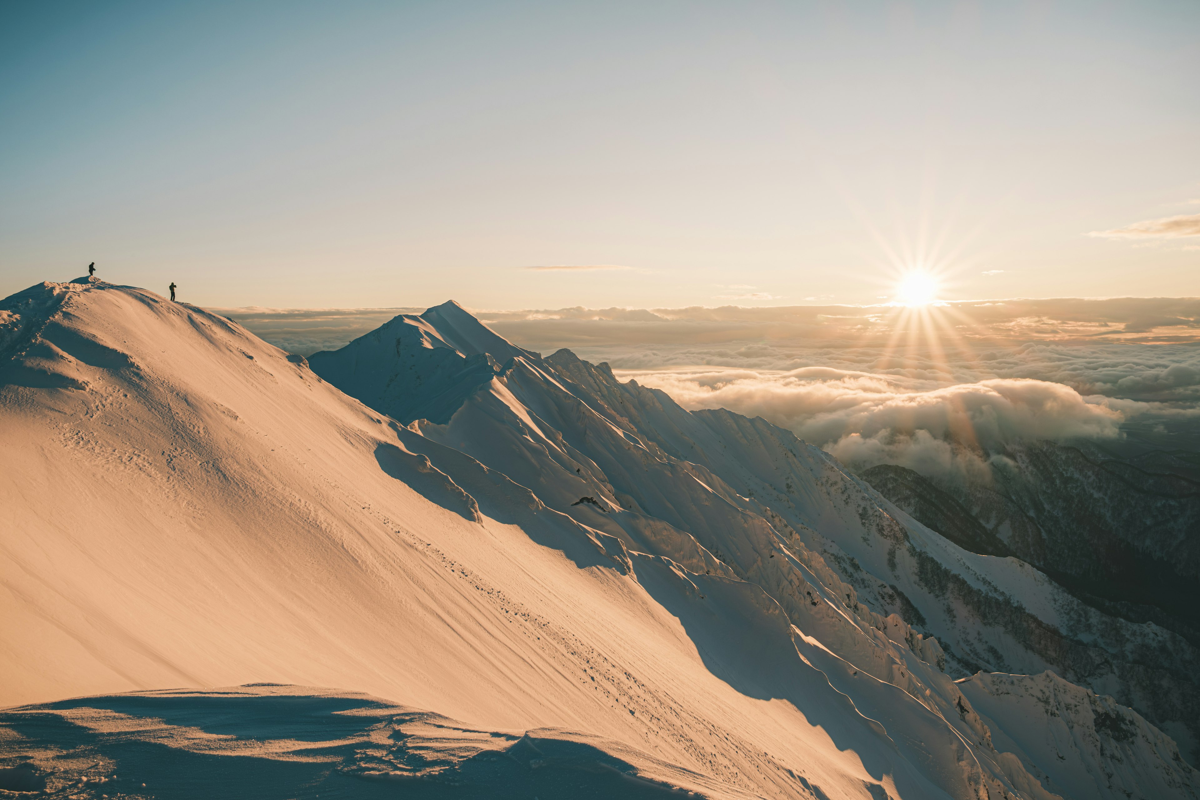 Cresta de montaña cubierta de nieve con amanecer al fondo