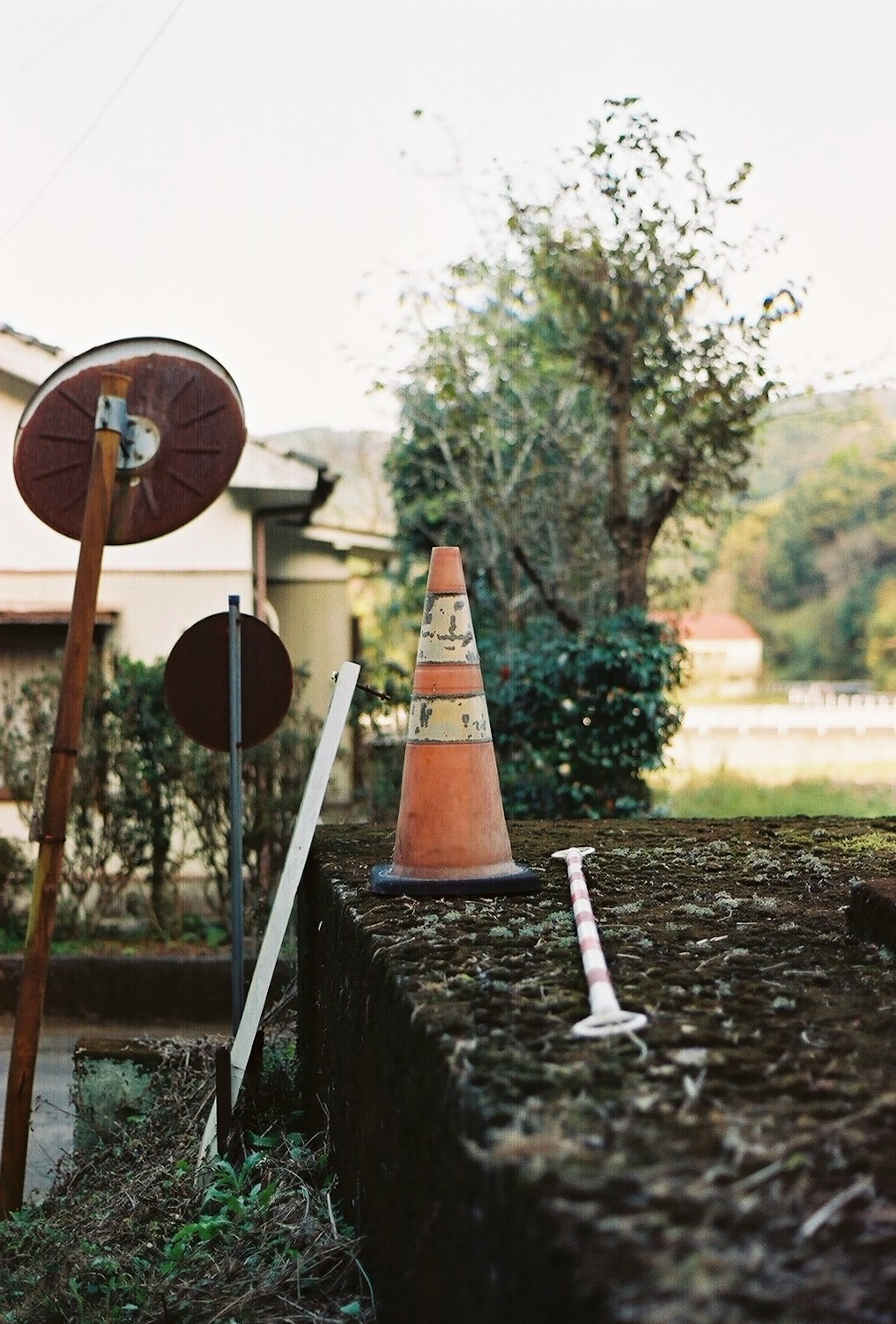 Oranger Verkehrshütchen und Spritze in einer Landschaft mit Bäumen und alten Schildern im Hintergrund