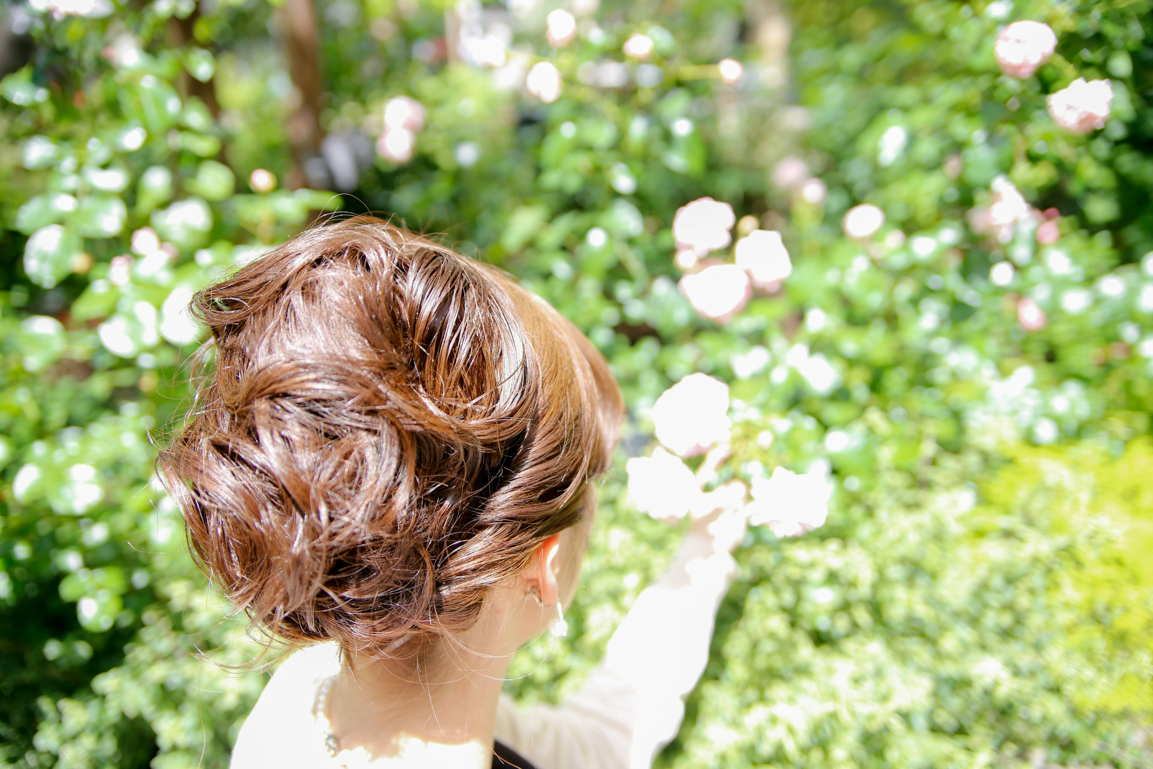 Woman holding pink roses in a lush green garden looking back