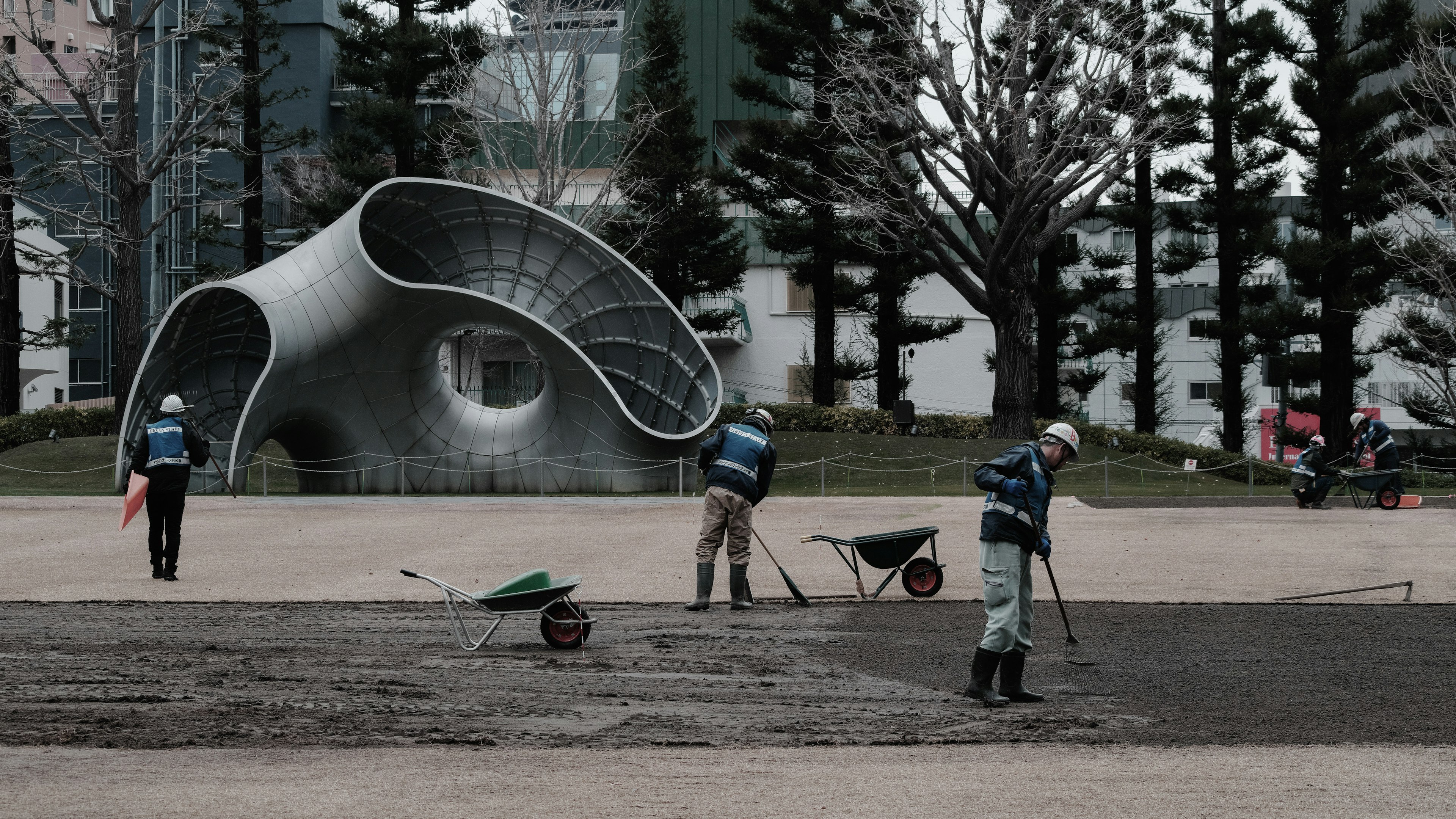 Travailleurs en train de paysager dans un parc avec une sculpture moderne