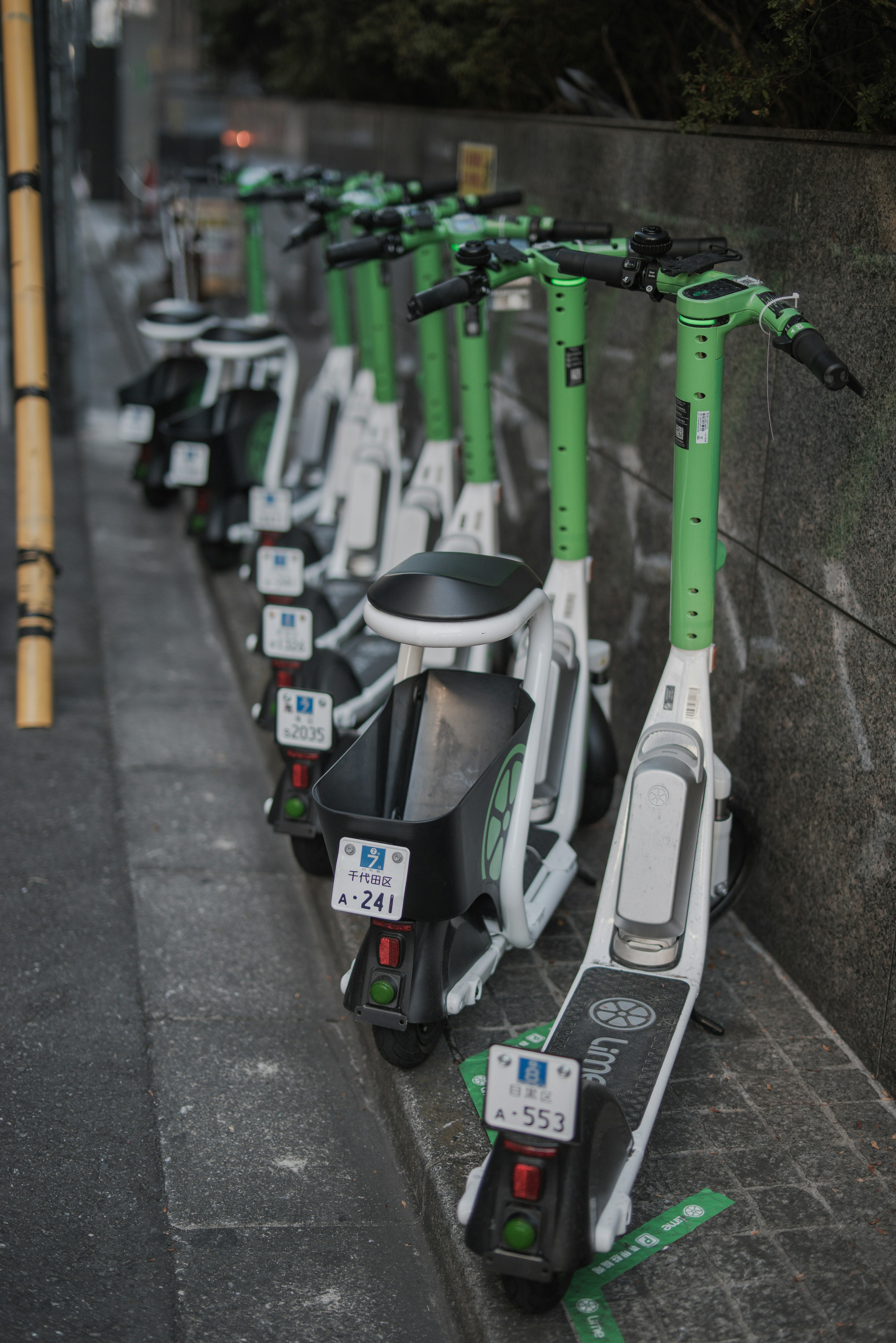 Row of white electric scooters with green handles