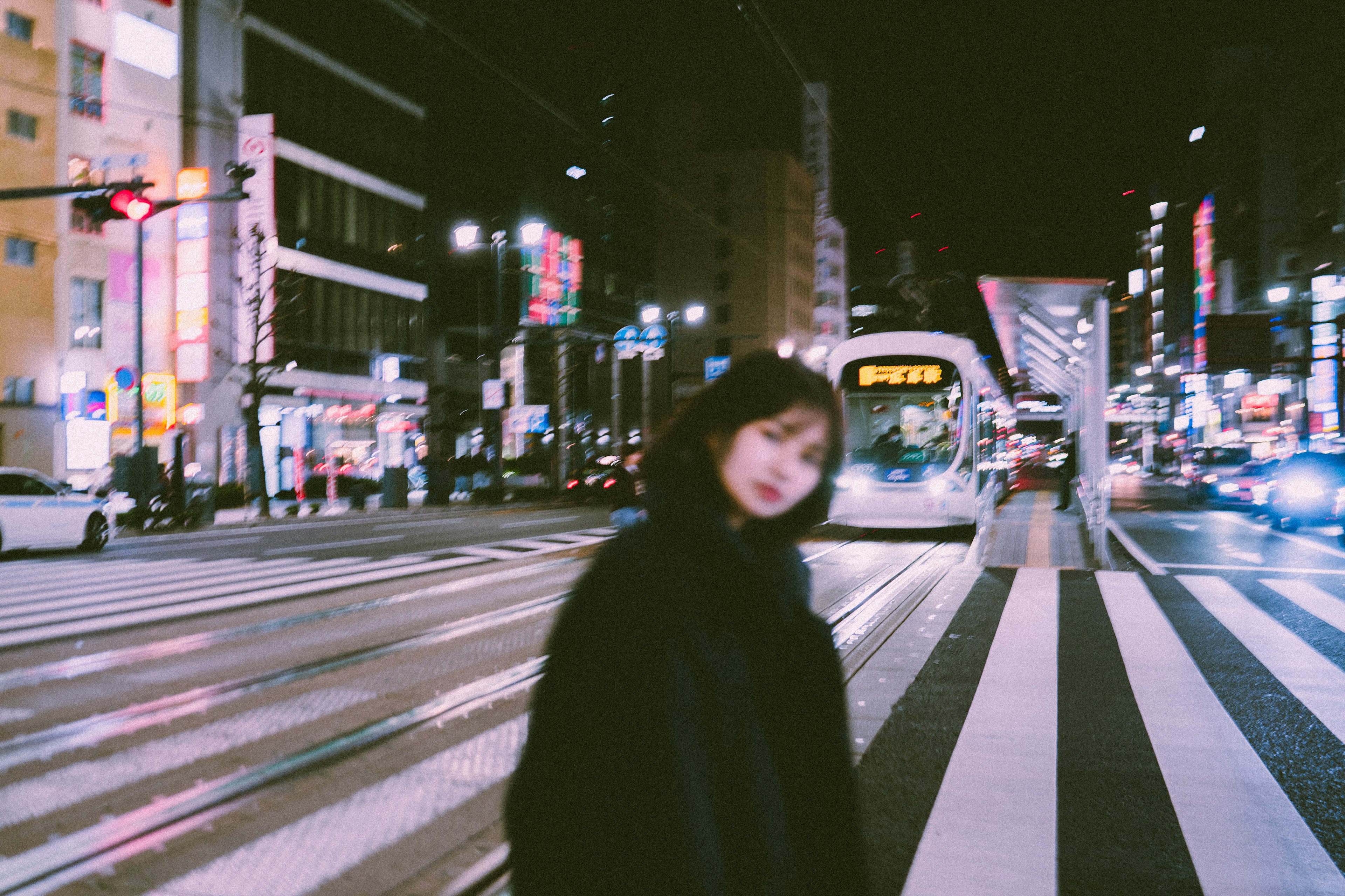 夜の街並みでぼやけた女性が歩く交差点の風景