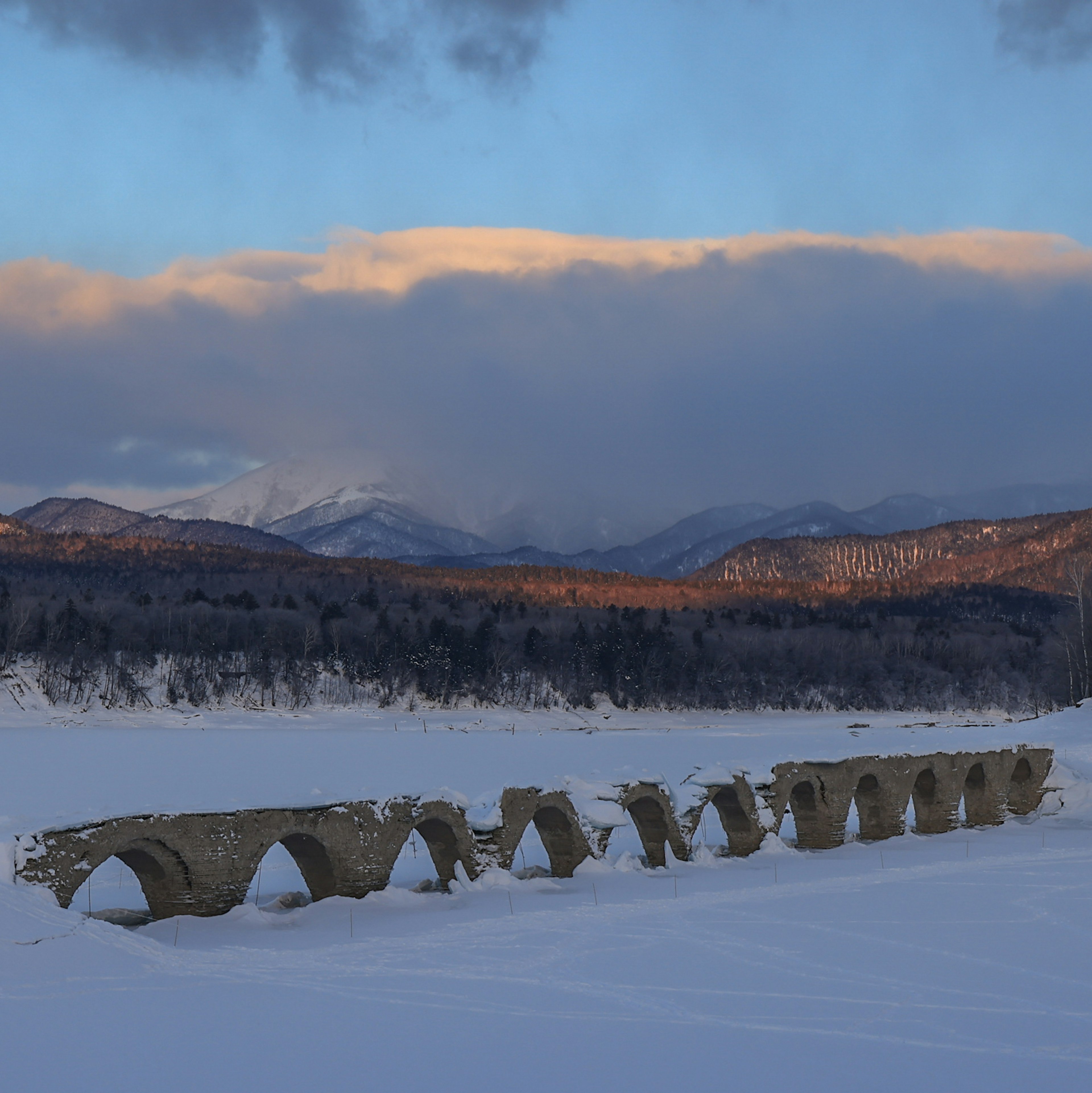 雪に覆われた風景にある古い石のアーチ