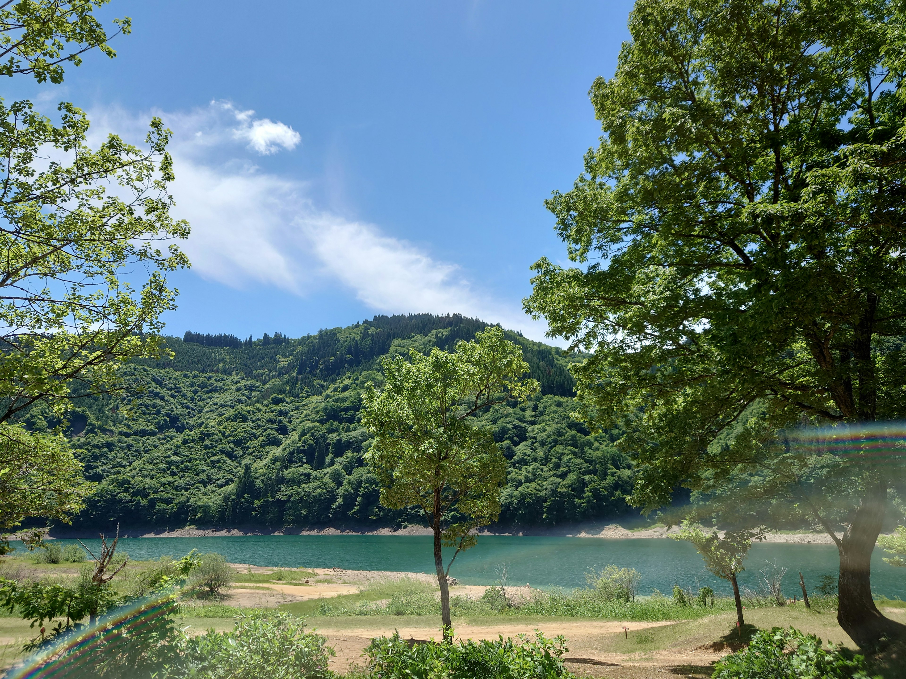 Malersiche Aussicht auf grüne Berge und einen blauen See unter klarem Himmel