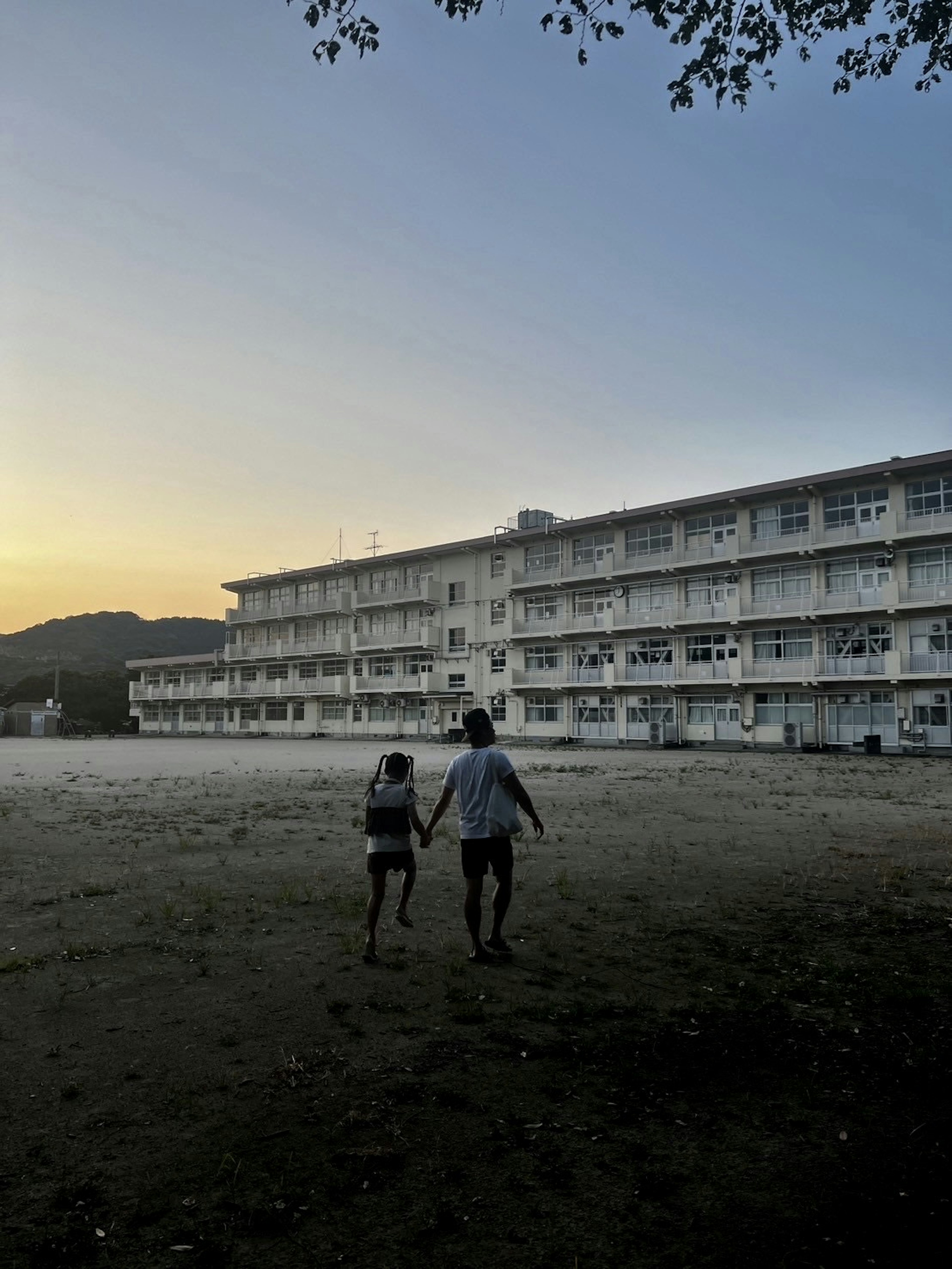 两个人在日落时分手牵手走在一座老建筑前