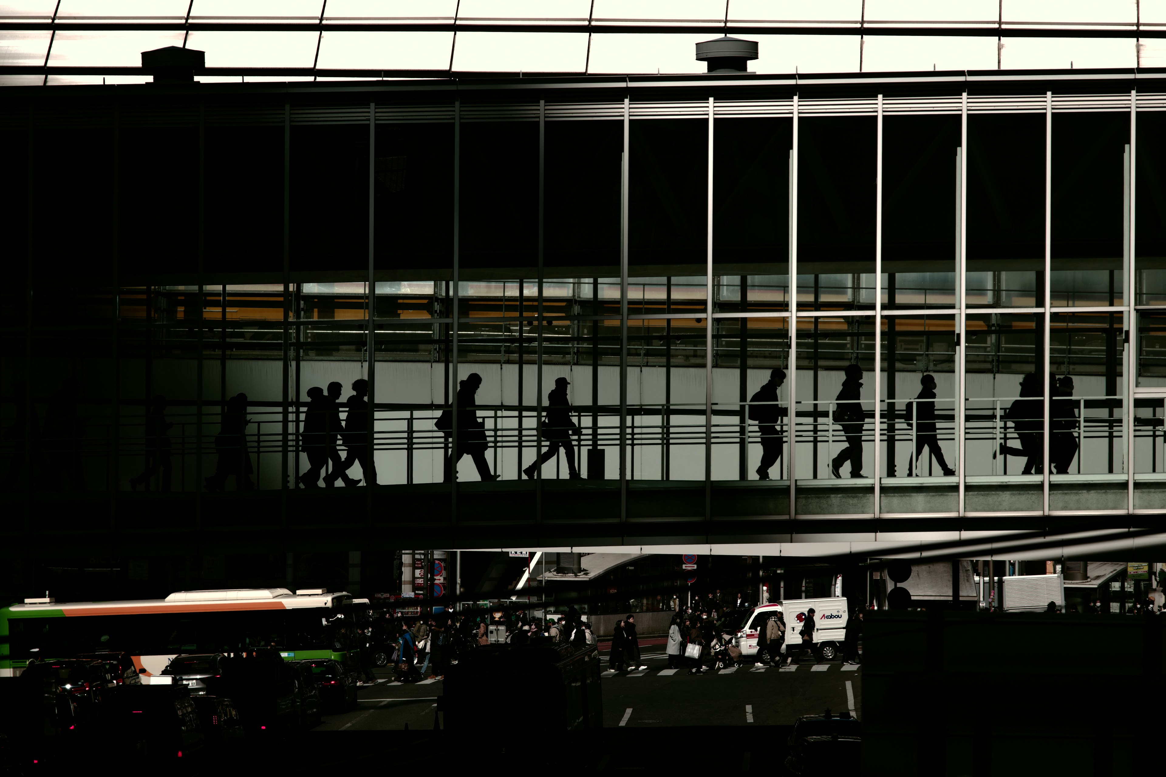 Silhouettes of people walking on a glass skybridge