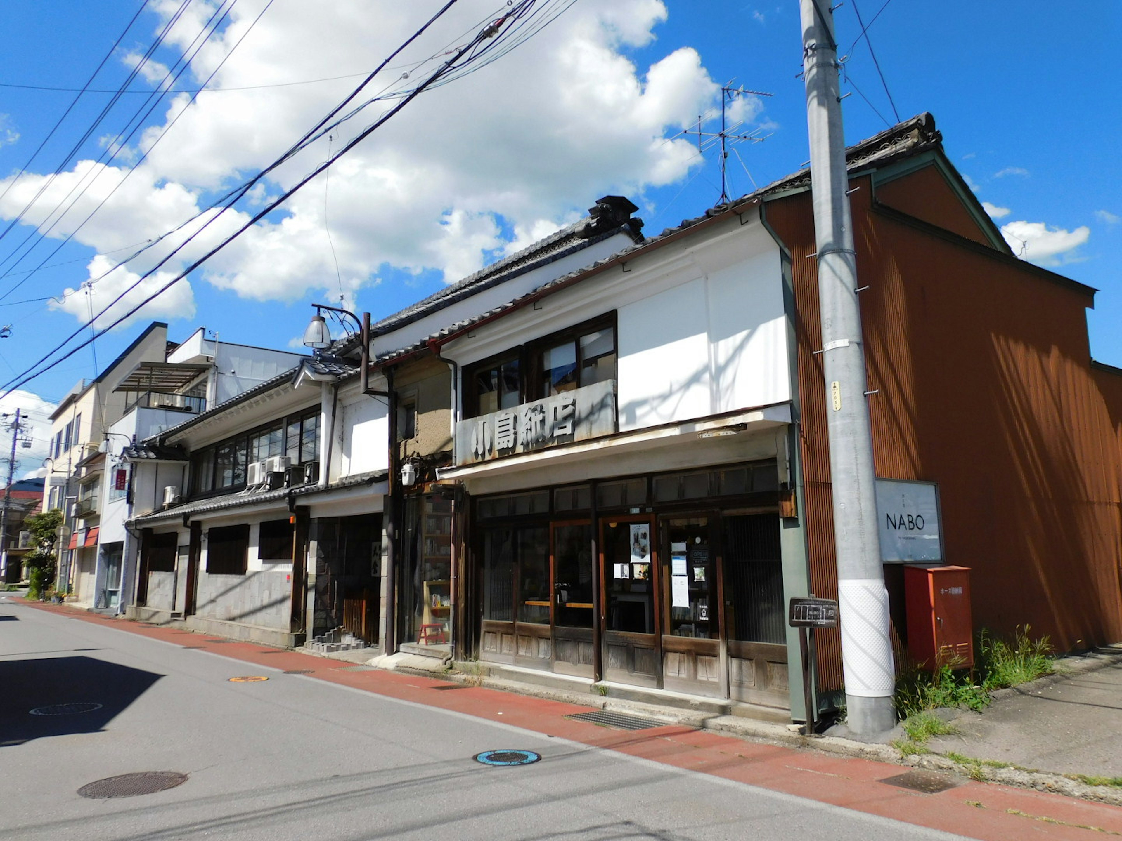 Vue de rue avec des bâtiments traditionnels japonais sous un ciel bleu clair et des nuages