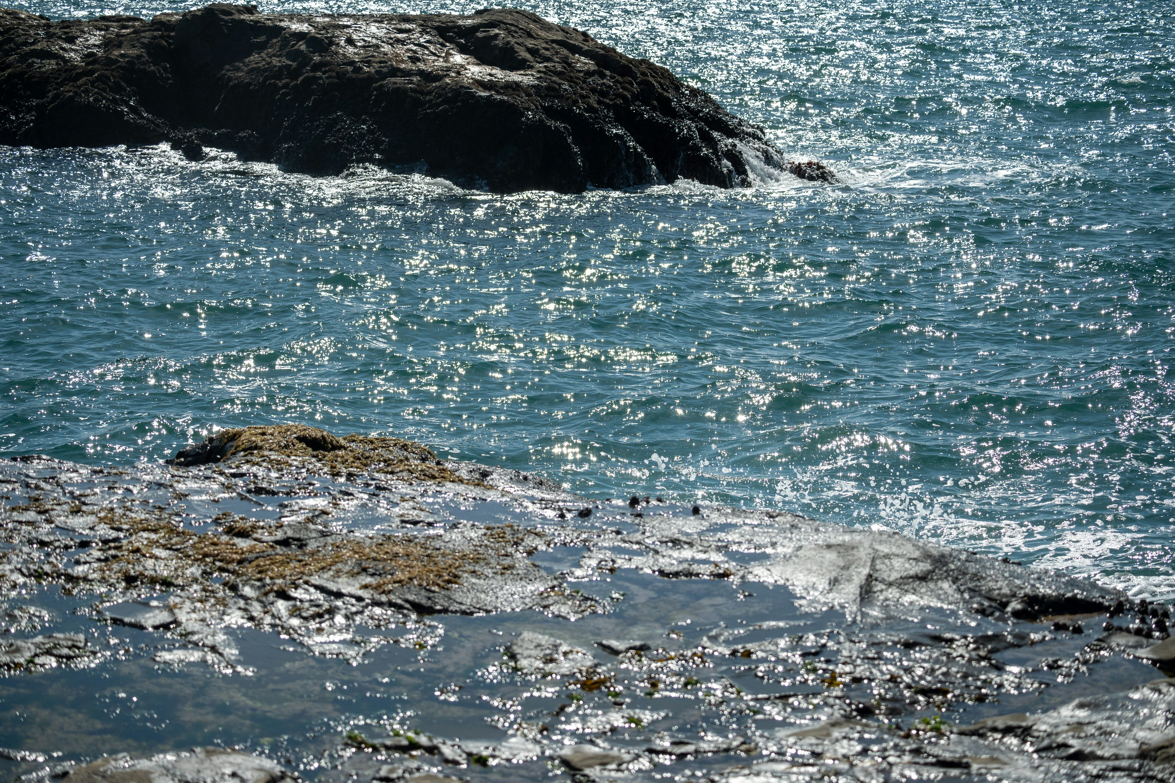 Blue sea with sparkling waves on rocky shore