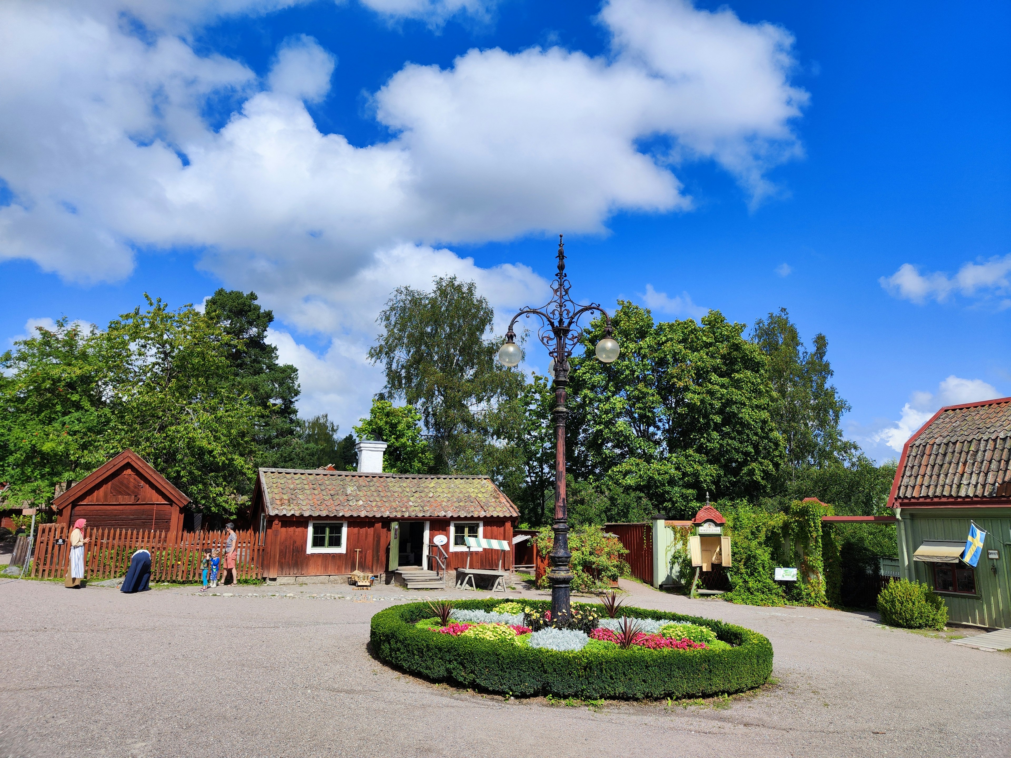 Scenic view of a red cabin and a white house under a blue sky with clouds