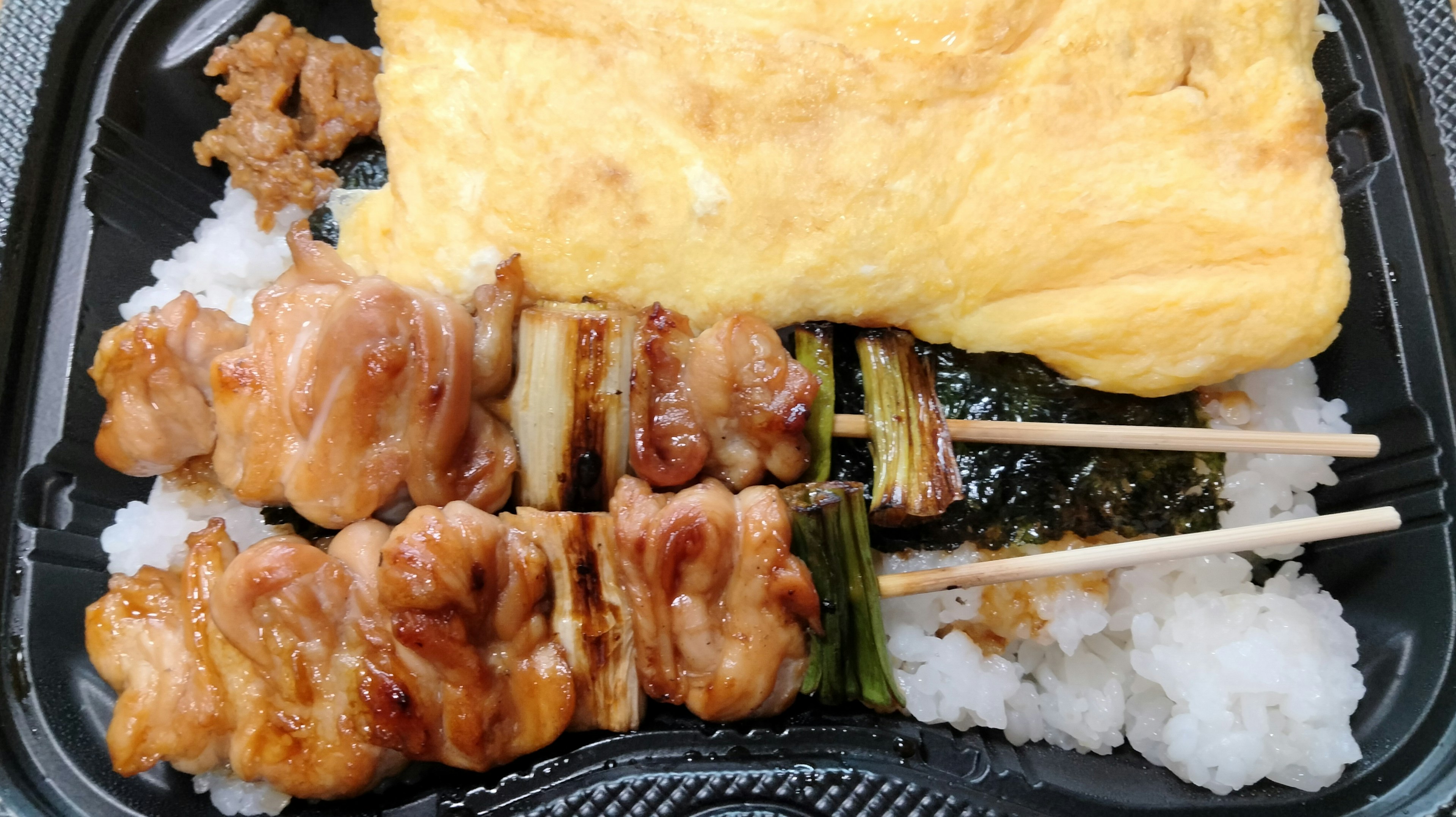 Caja bento con brochetas de pollo a la parrilla y una tortilla