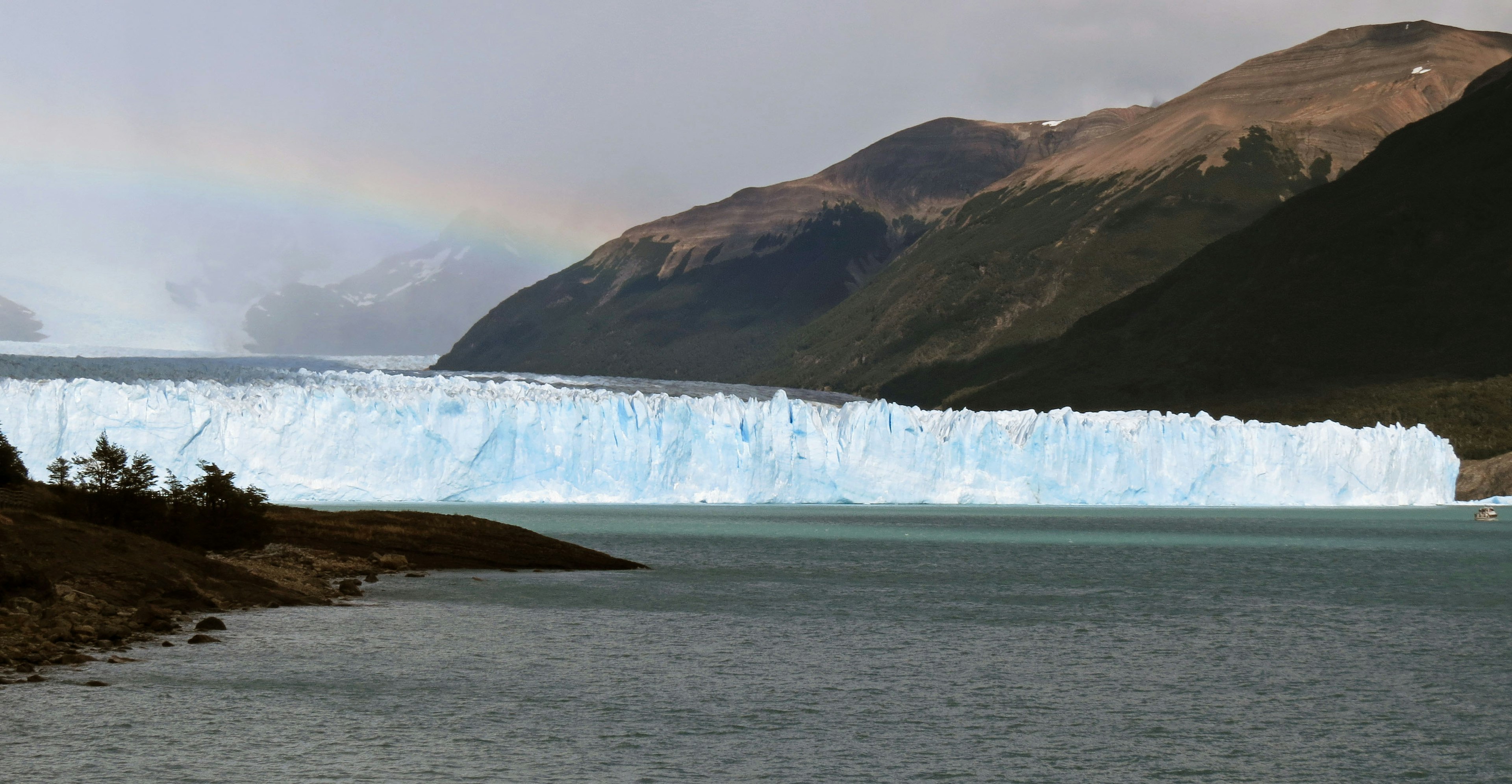 Glaciar azul rodeado de montañas y lago