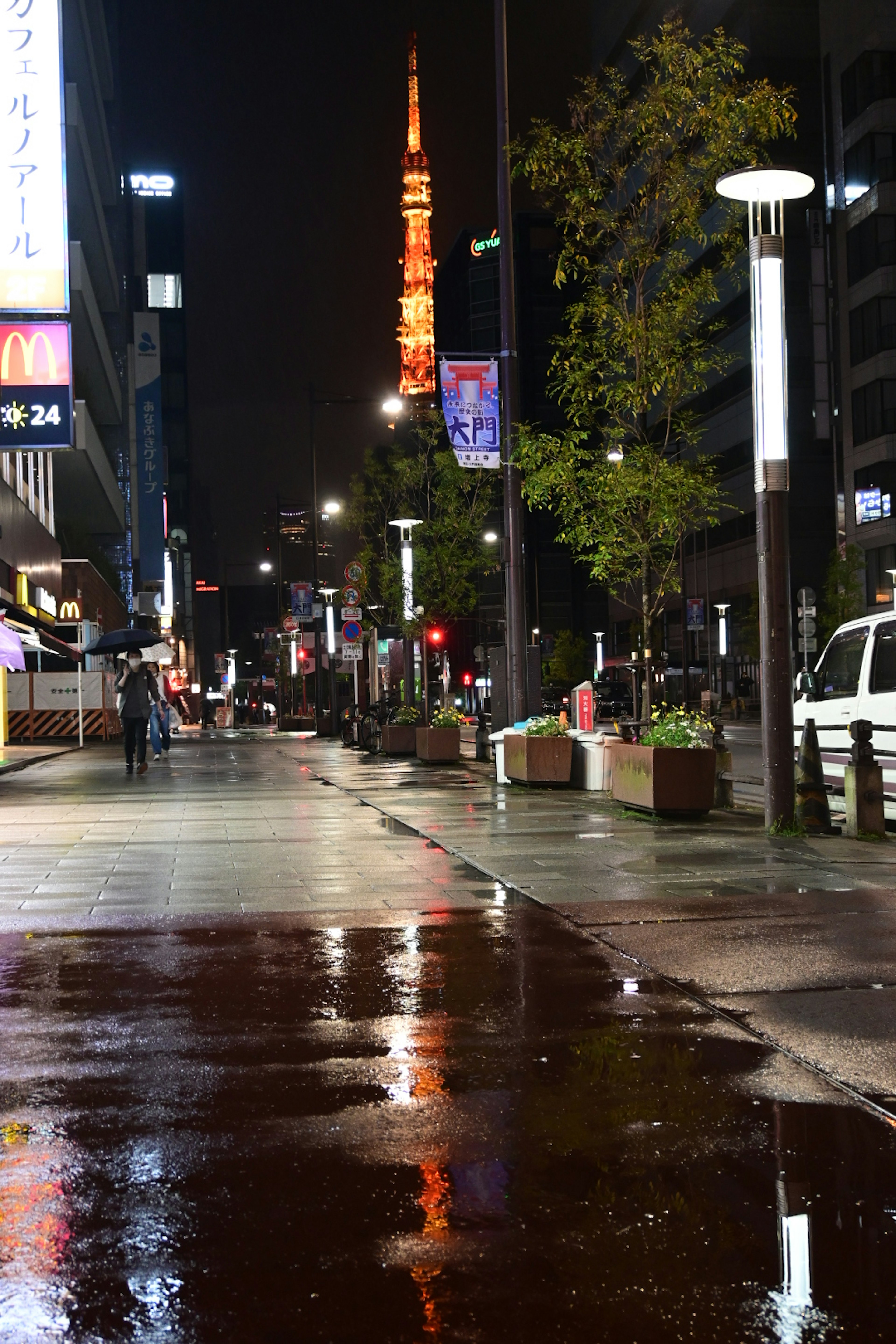 Vista nocturna de la Torre de Tokio iluminada con reflejos en el pavimento mojado