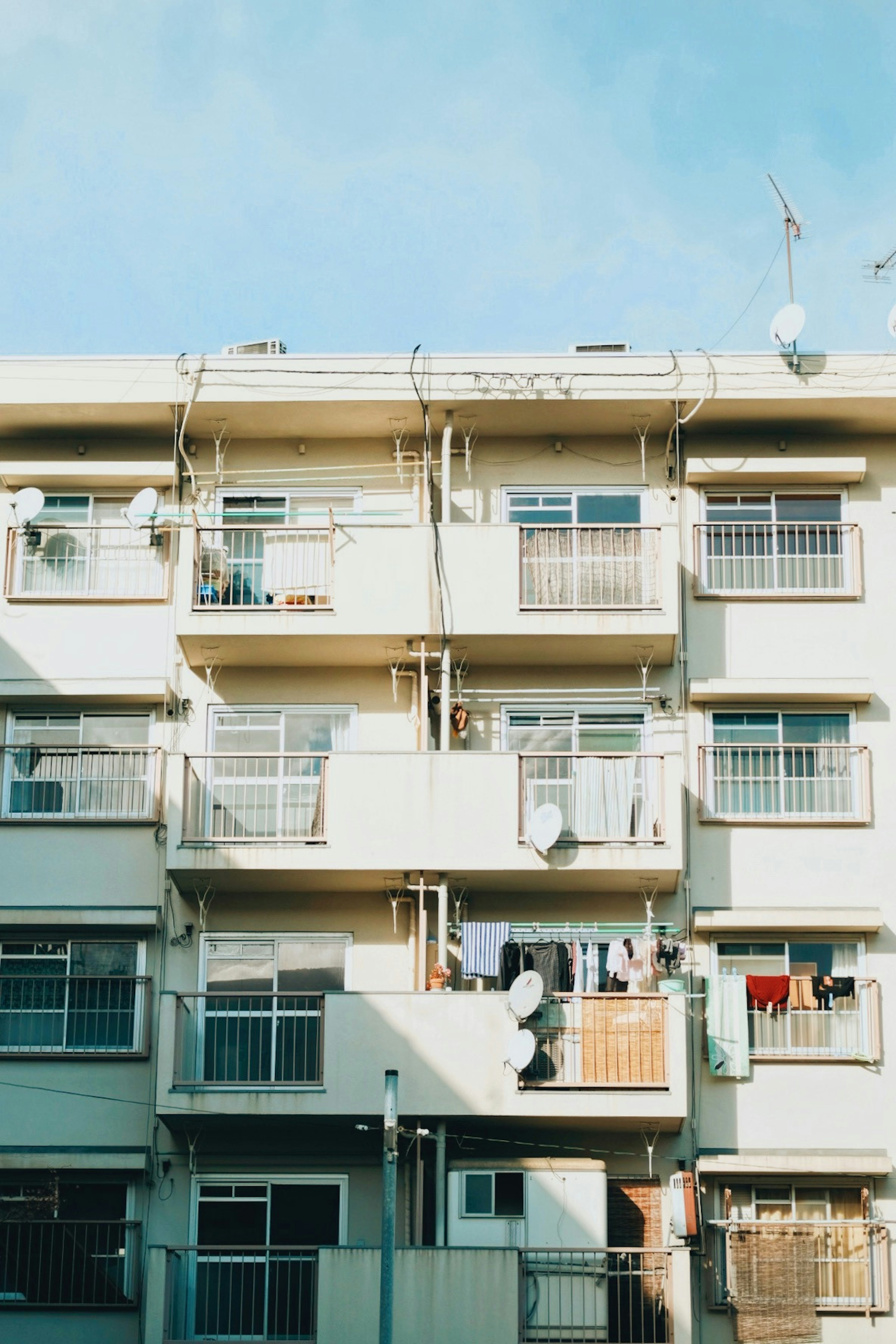 Vista esterna di un edificio residenziale sotto un cielo blu bucato appeso alle finestre