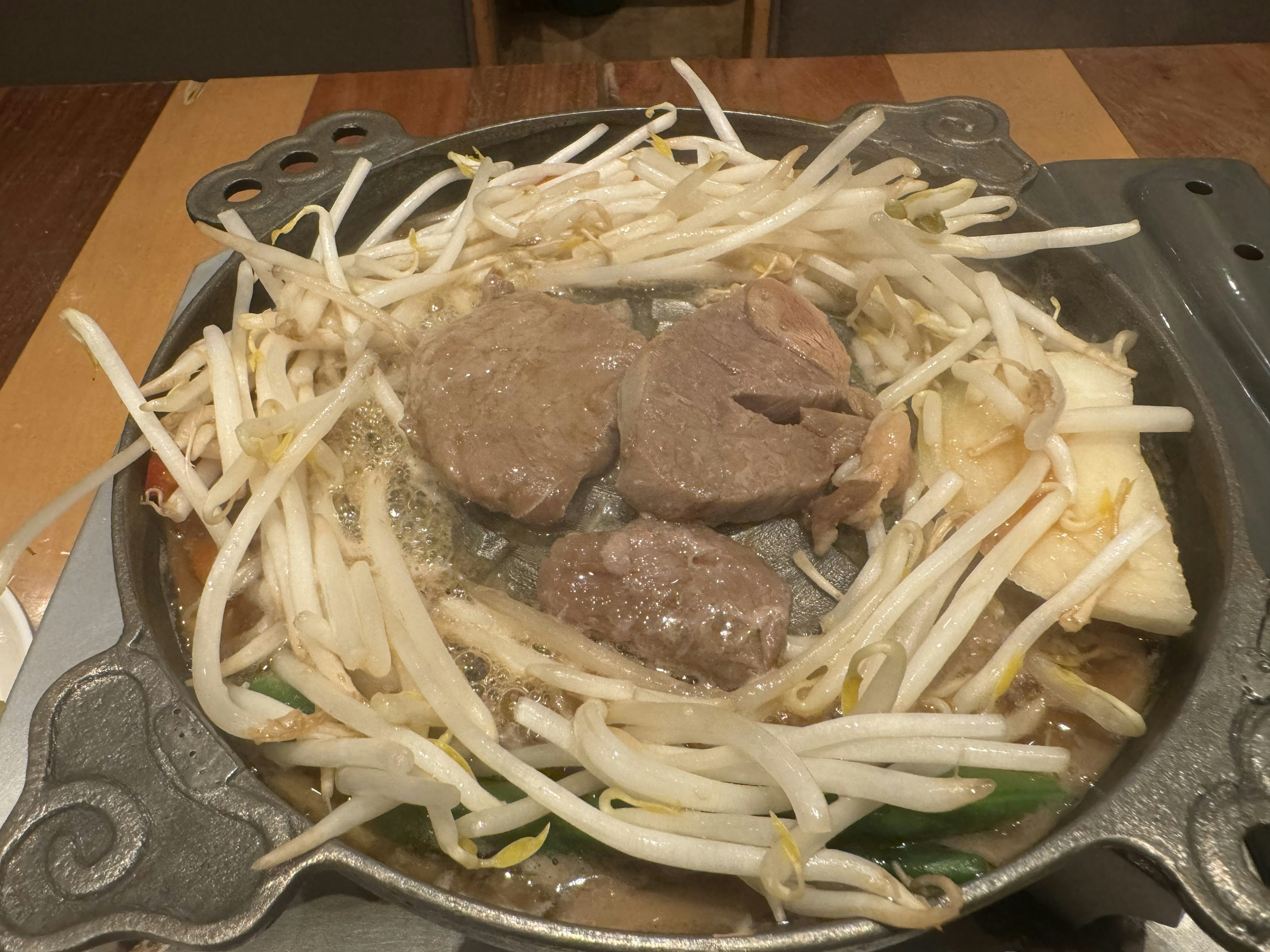 A hot pot with beef slices and bean sprouts