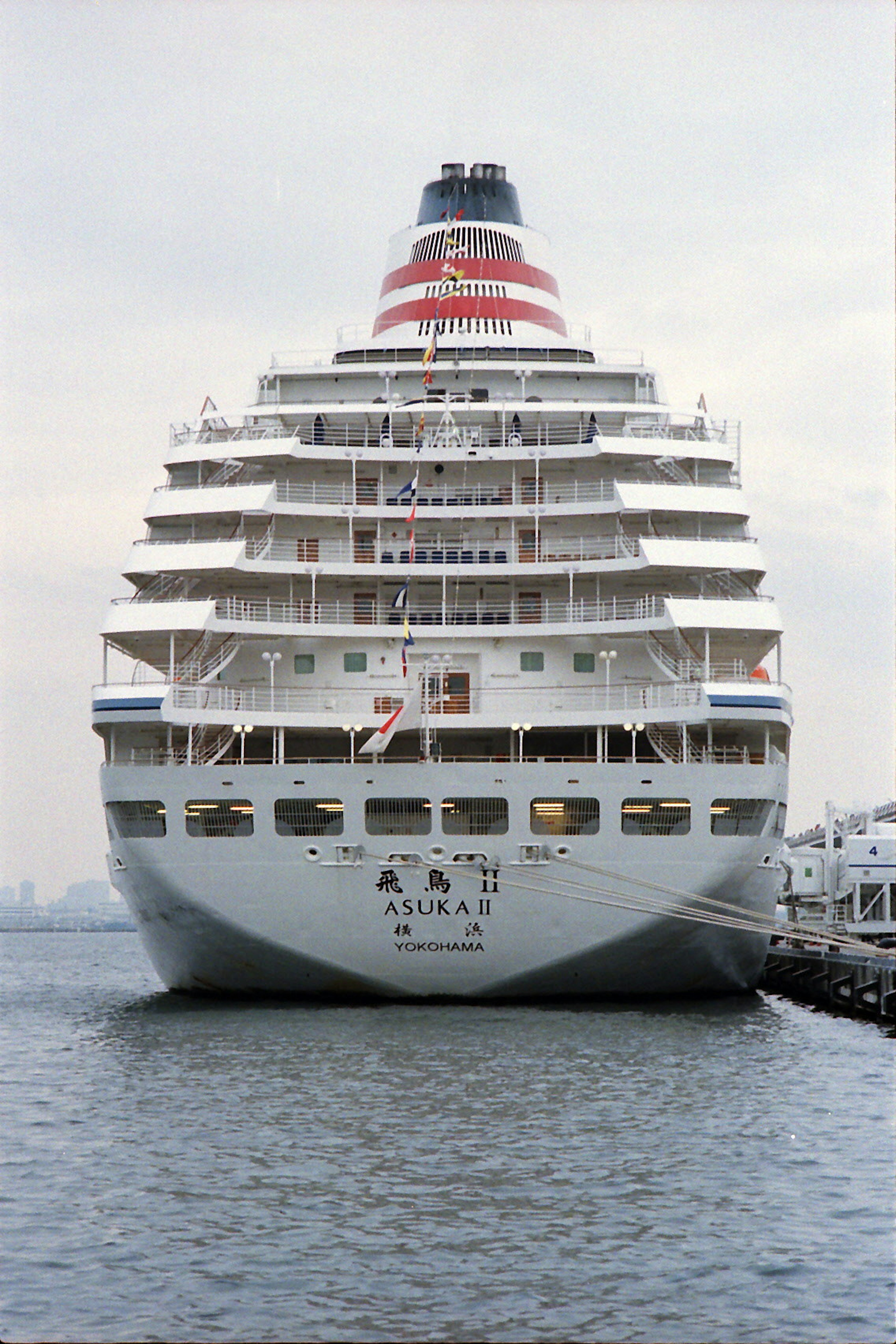 Large cruise ship docked at the port with its bow reflecting on the water