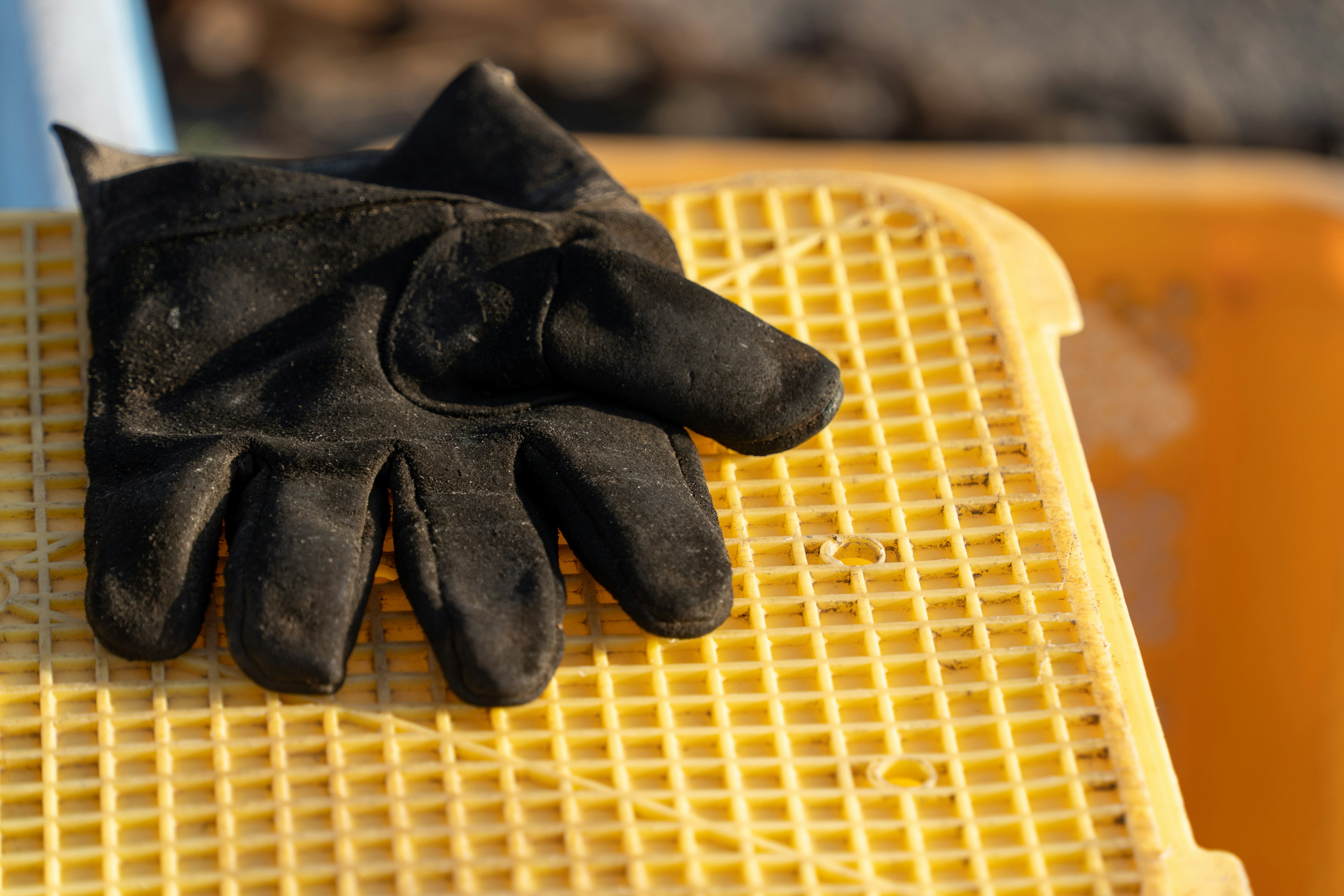 Black glove resting on a yellow mesh surface