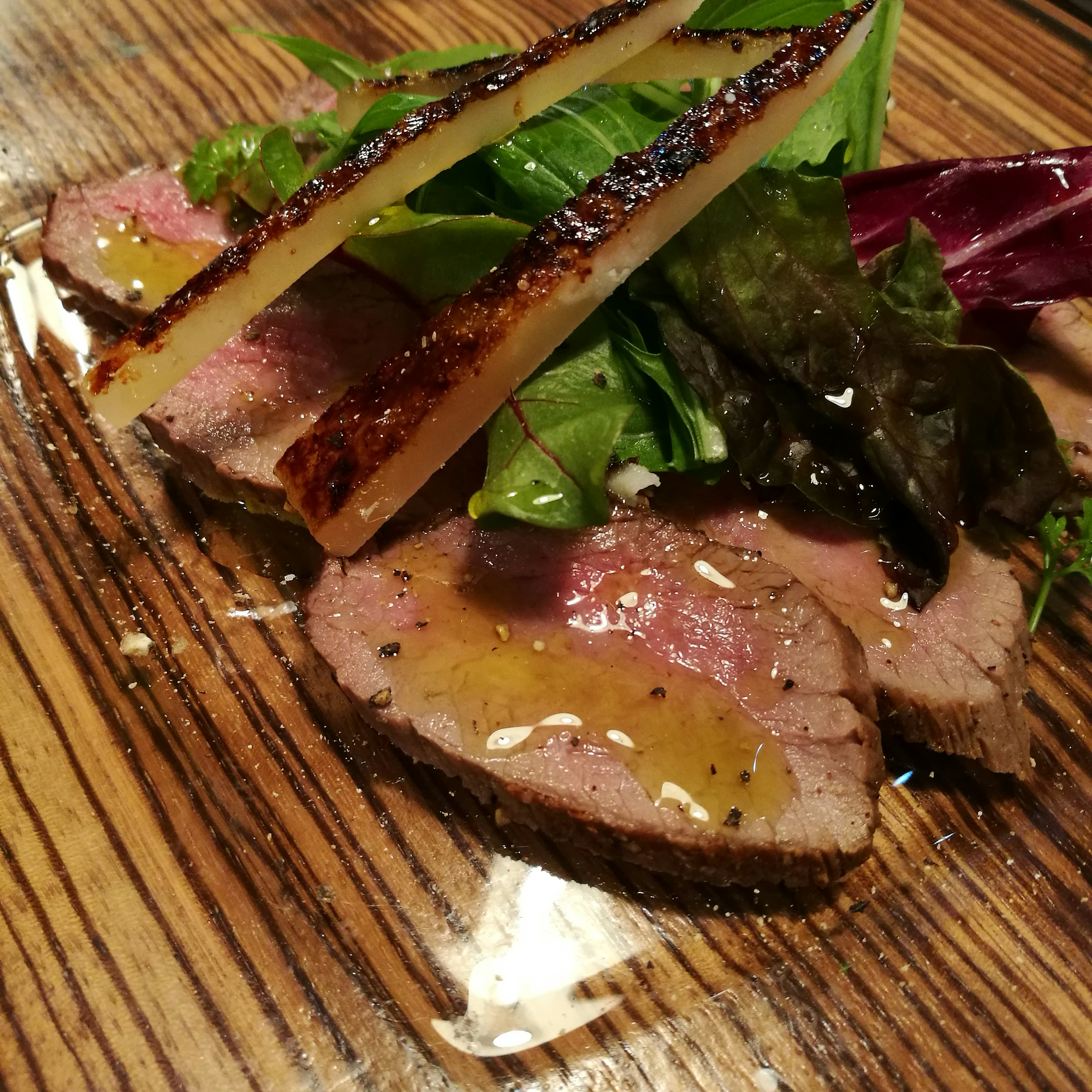 Carne en rodajas finas cubierta con verduras frescas y salsa