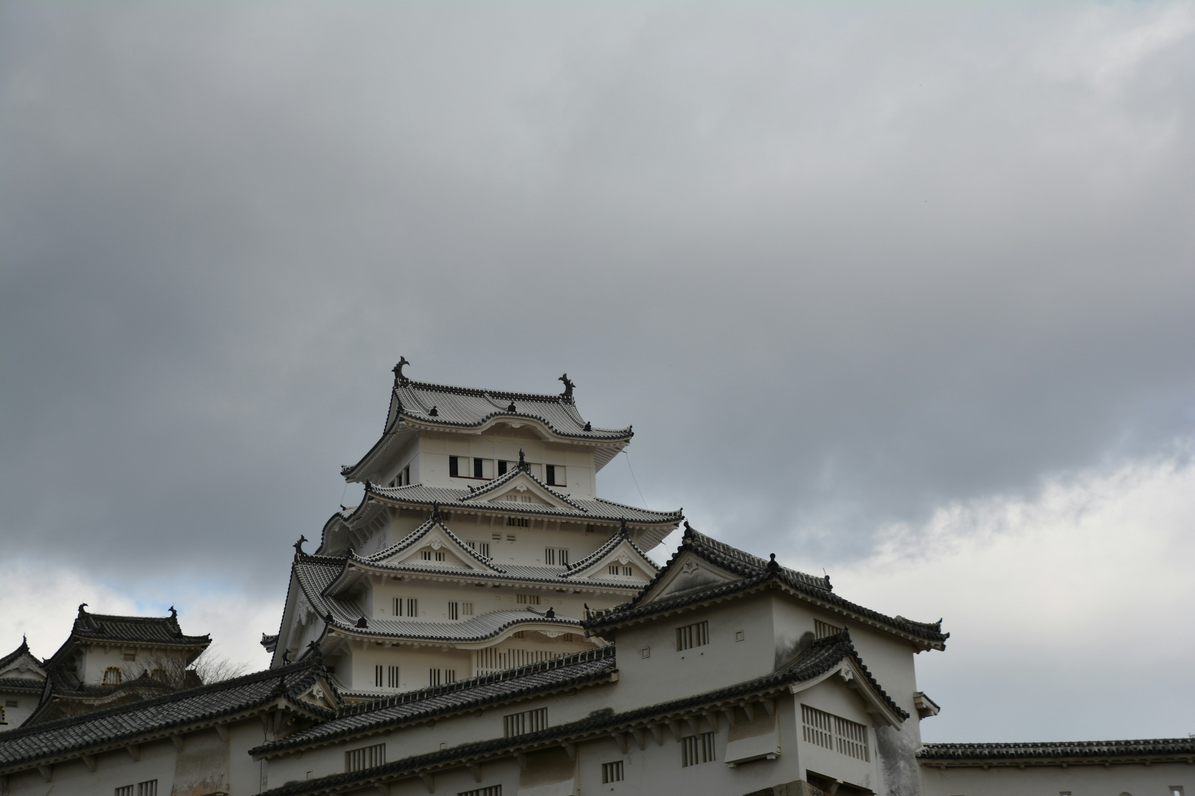 Himeji Castle with intricate roof details under a cloudy sky