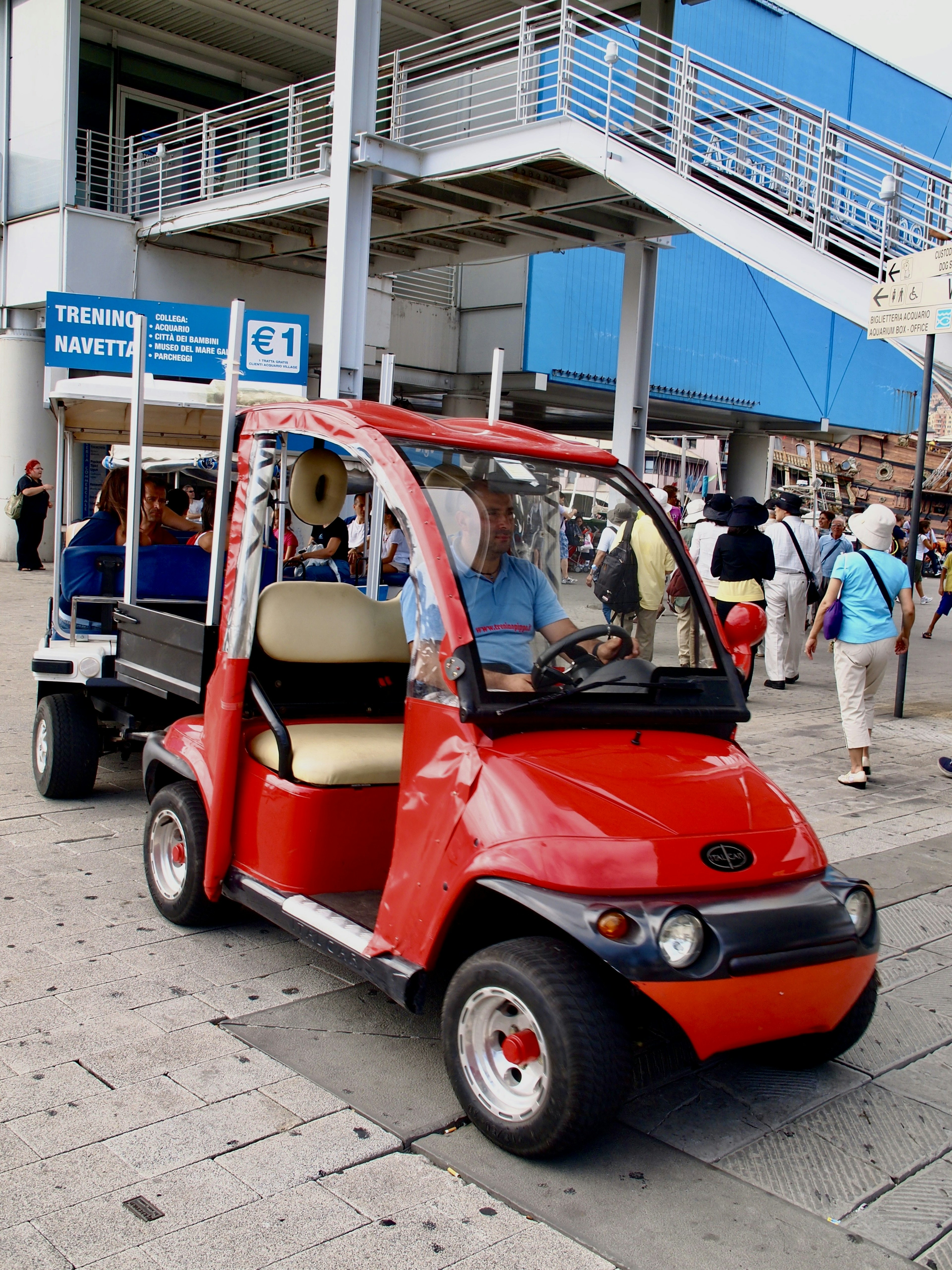 Sebuah kereta golf elektrik merah berhenti di trotoar