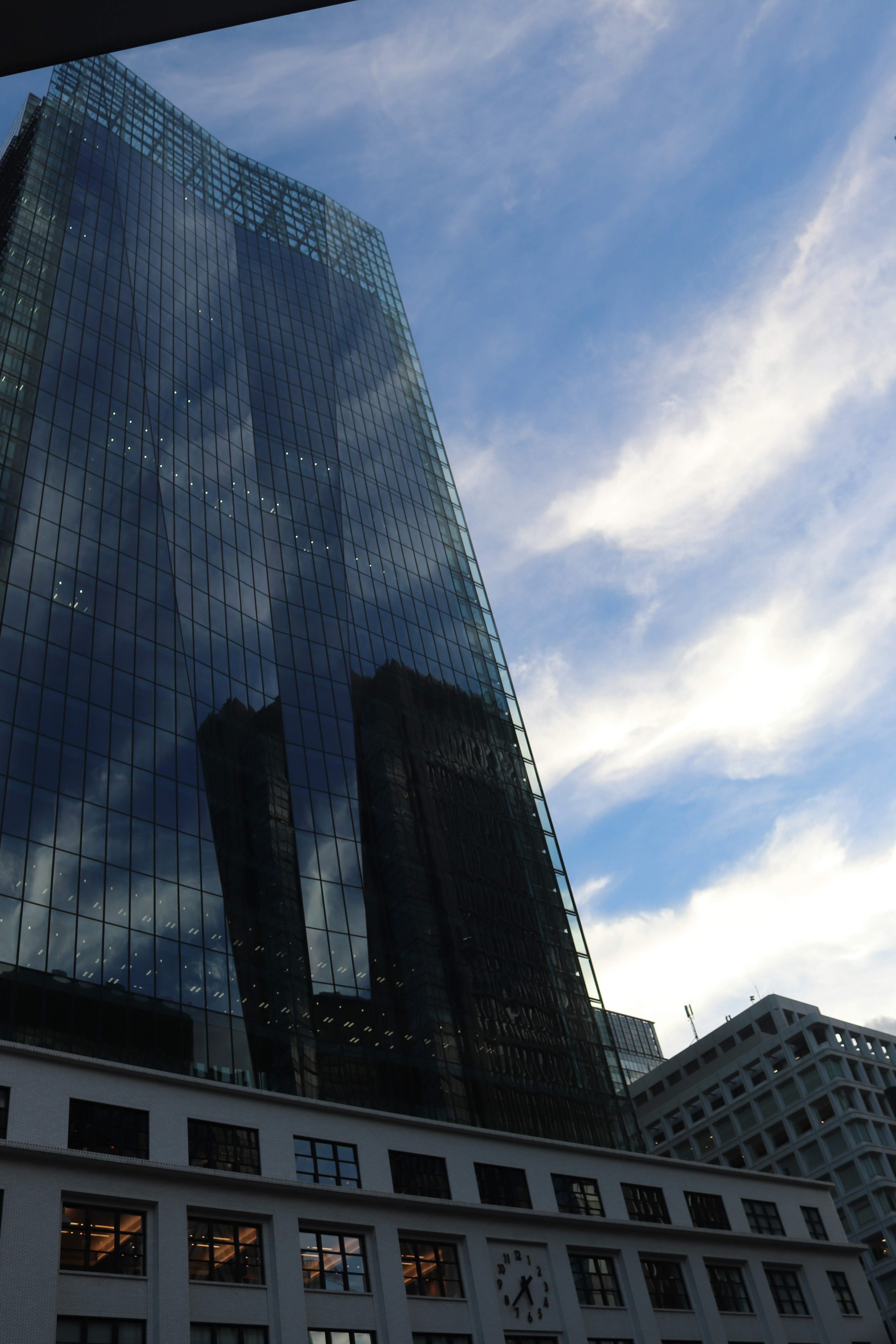 Wolkenkratzer mit Glasfassade, die den blauen Himmel spiegelt