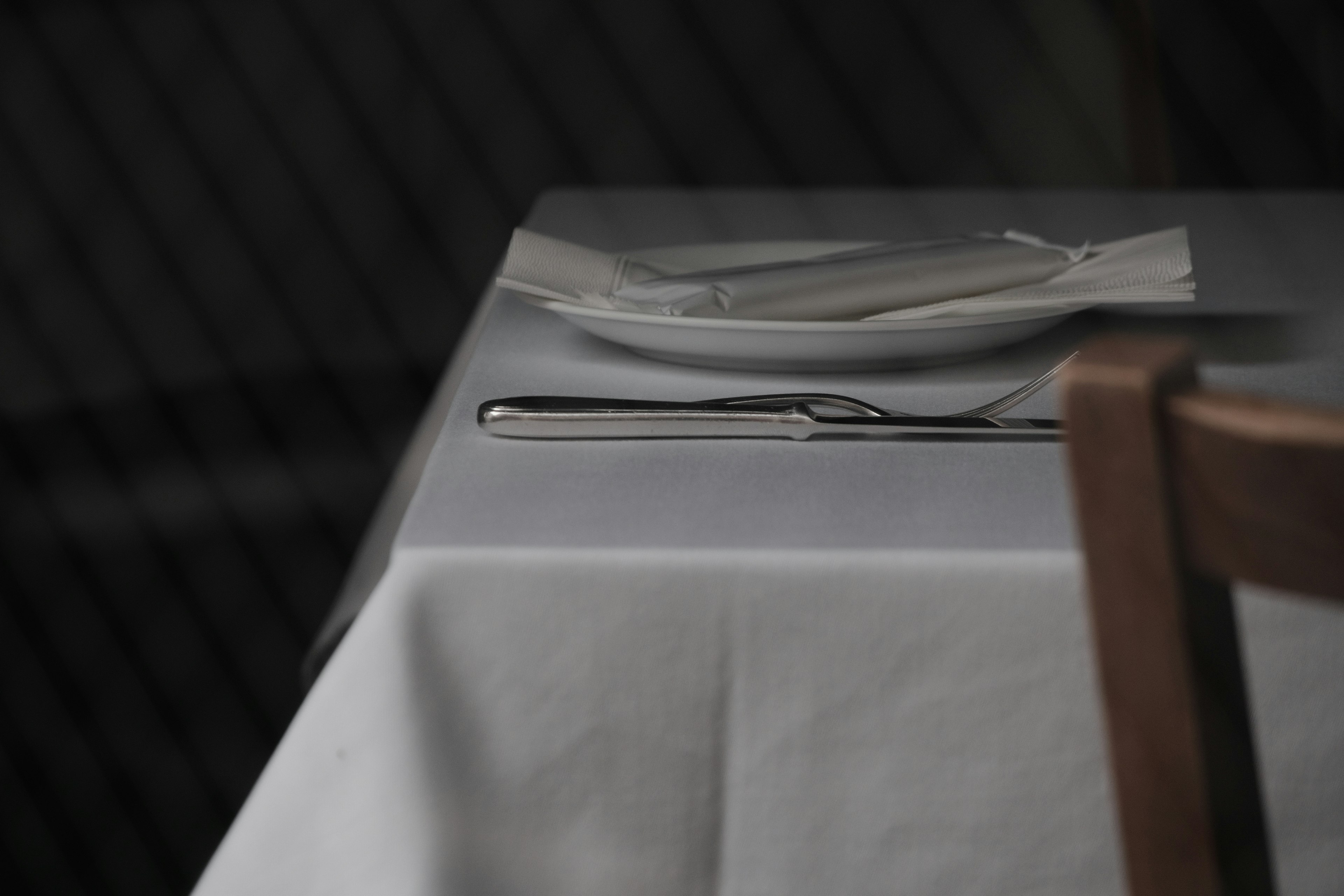 A serene scene of a plate and cutlery on a white tablecloth