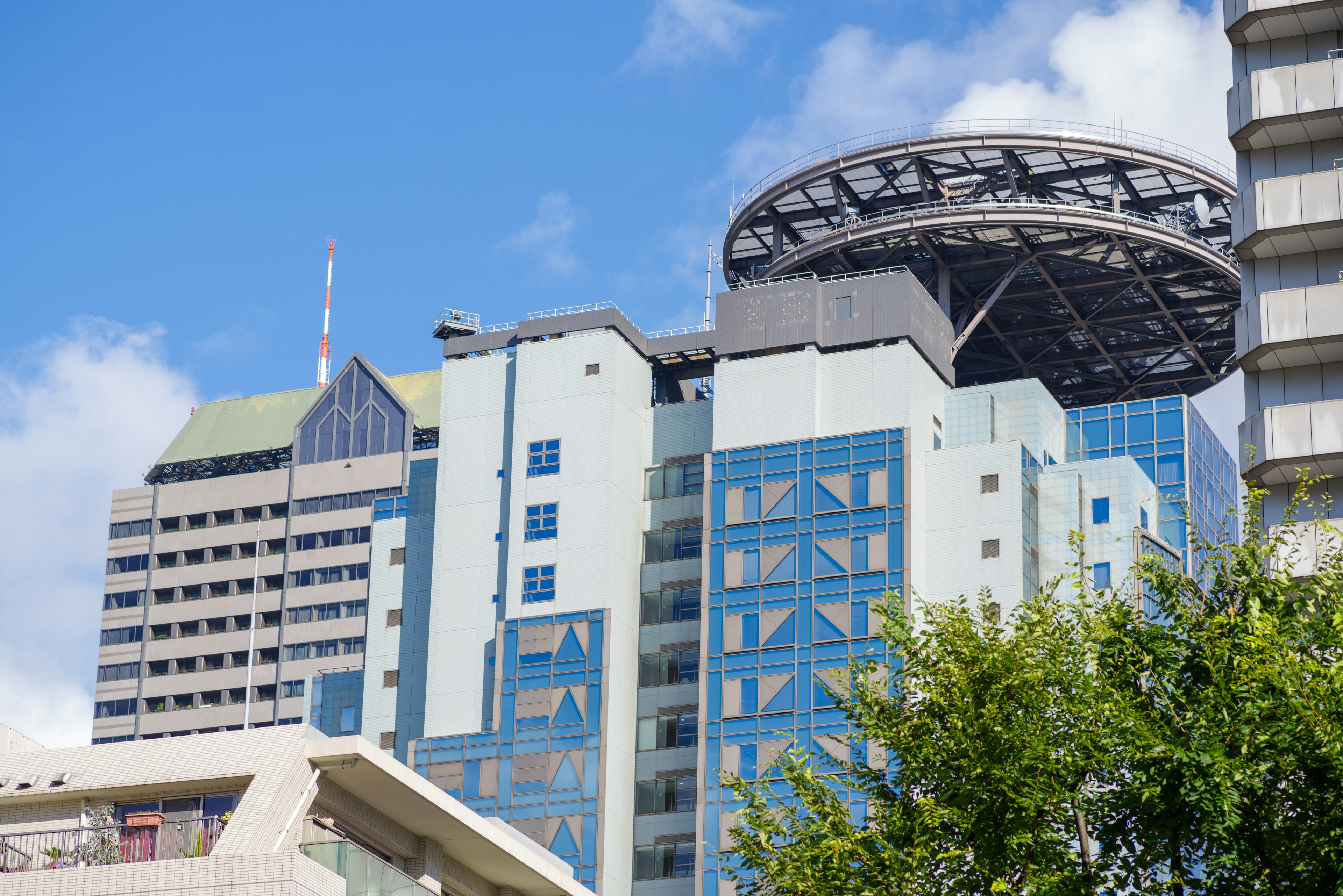 Modern buildings with unique rooftop design under clear blue sky