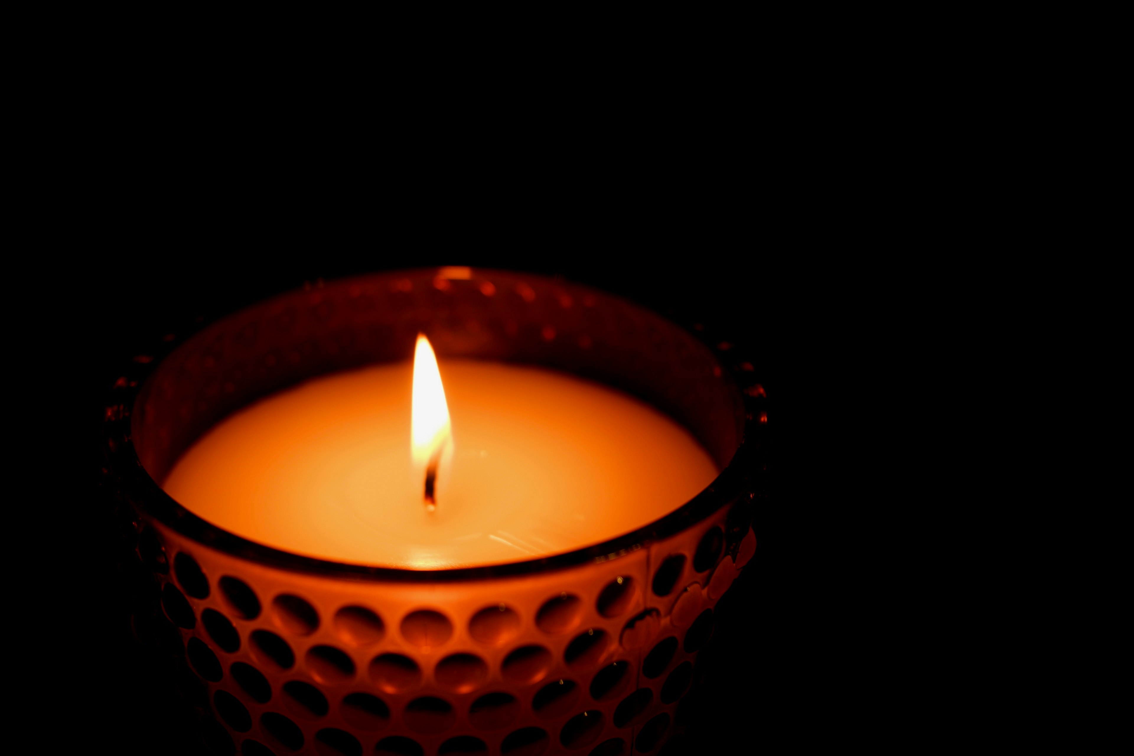 A lit orange candle glowing against a dark background