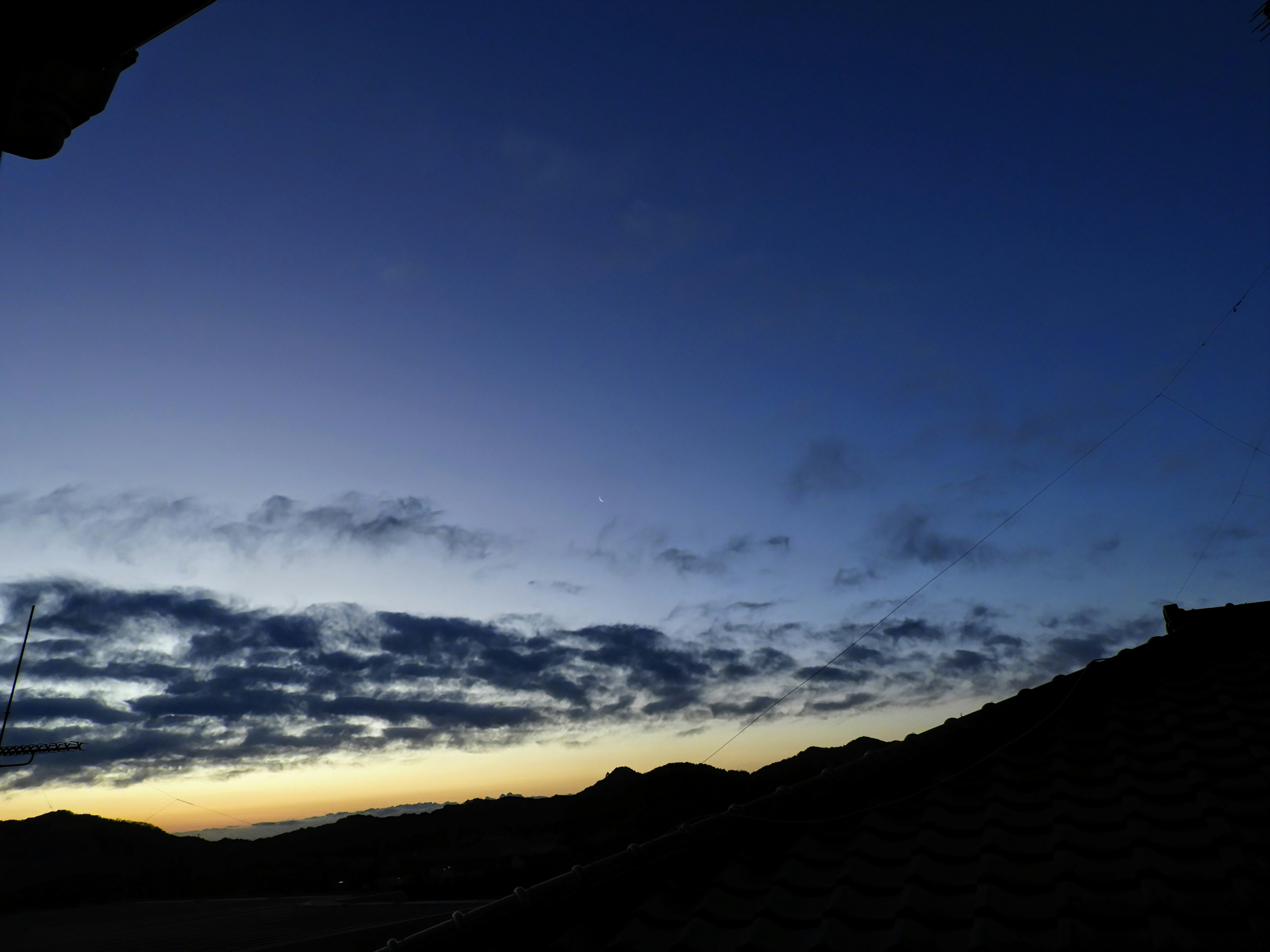 Langit senja dengan nuansa biru dan awan siluet atap