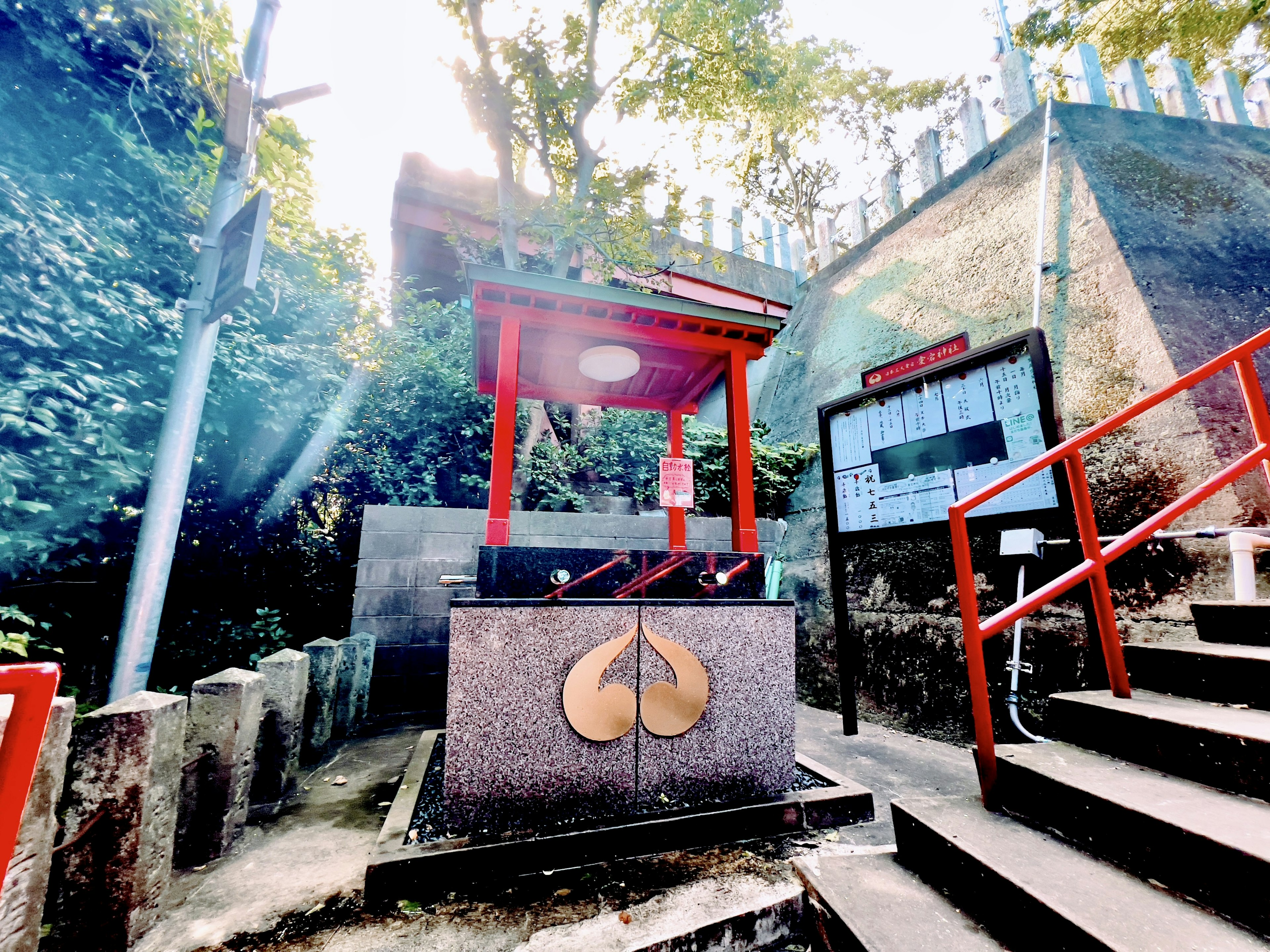 Scenic view of a shrine entrance featuring a red torii gate and a stone pedestal