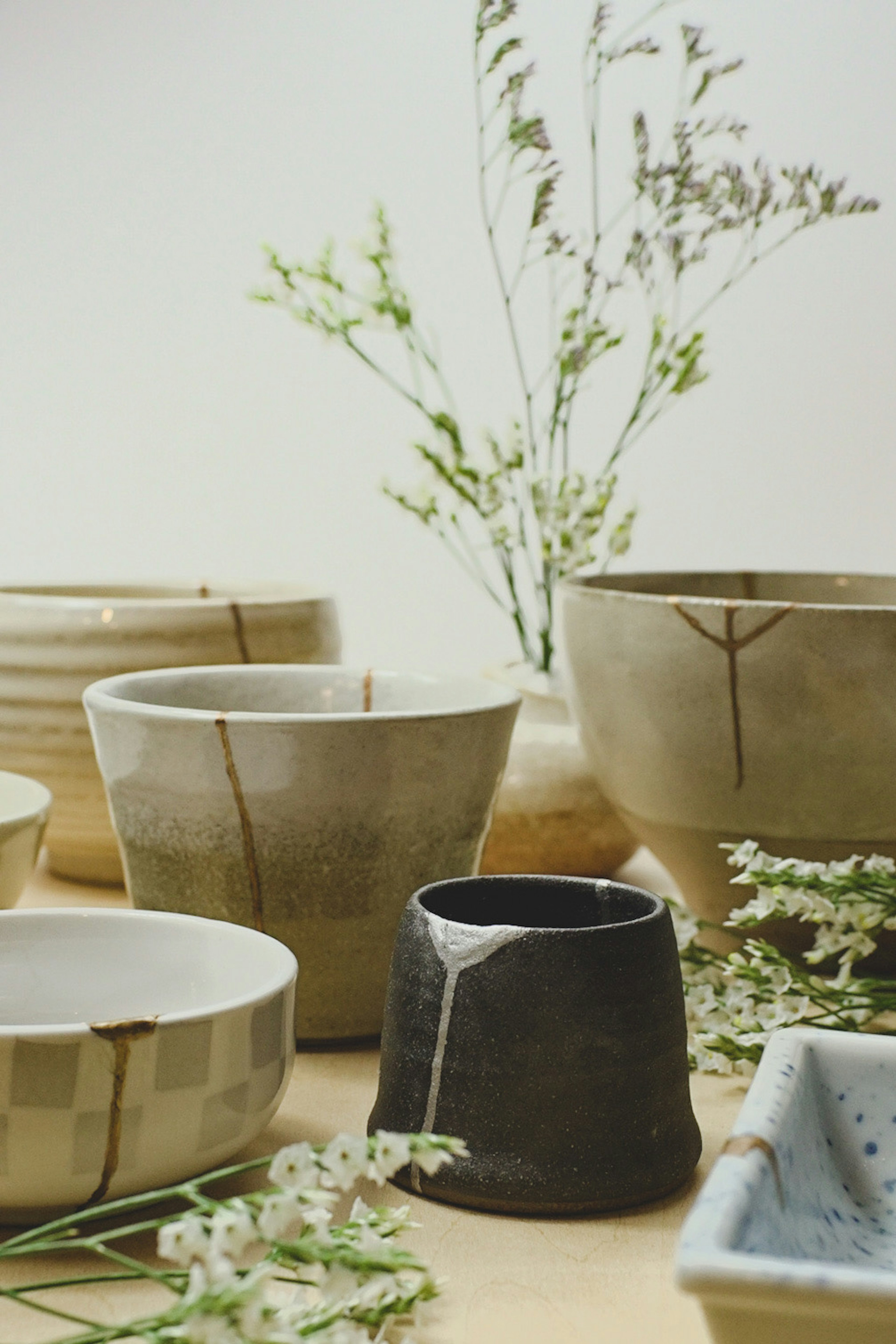 Various shapes and colors of ceramic bowls arranged with flowers