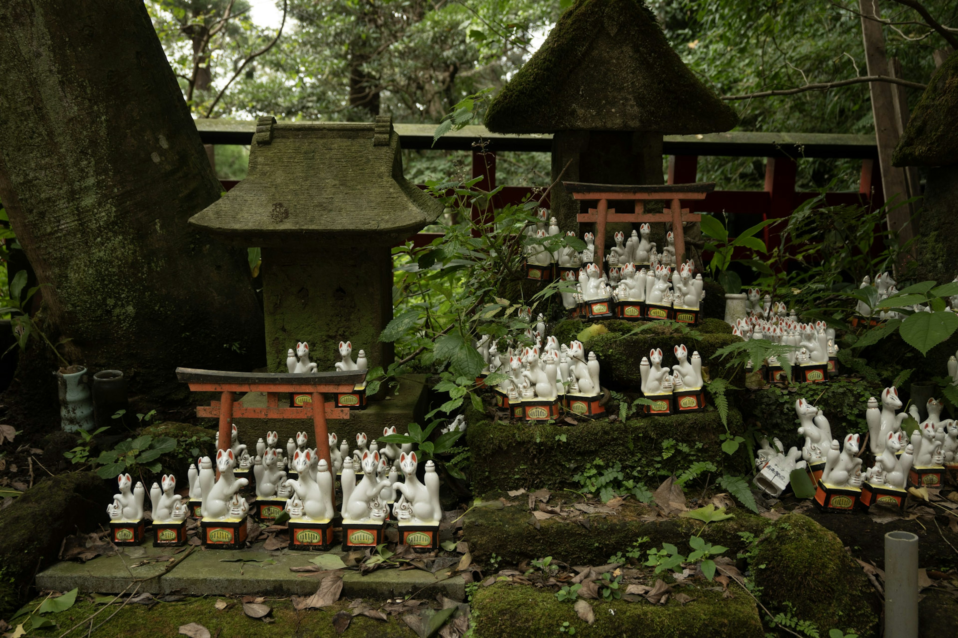 一个宁静的景观，包含一个小神社和许多白色雕像，环绕在绿色植物中