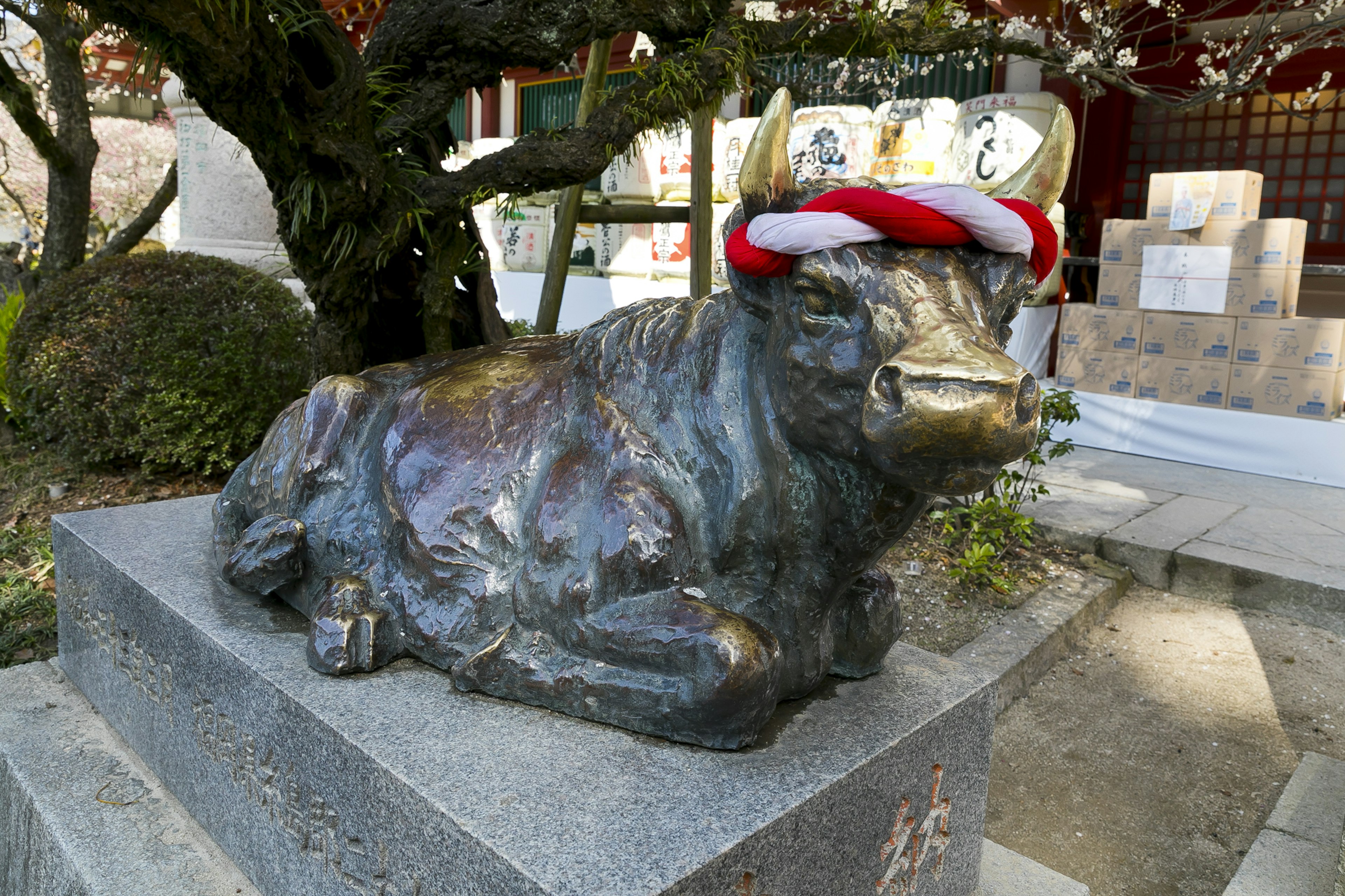 Eine Bronzestatue eines liegenden Bullen mit einem rot-weißen Hut