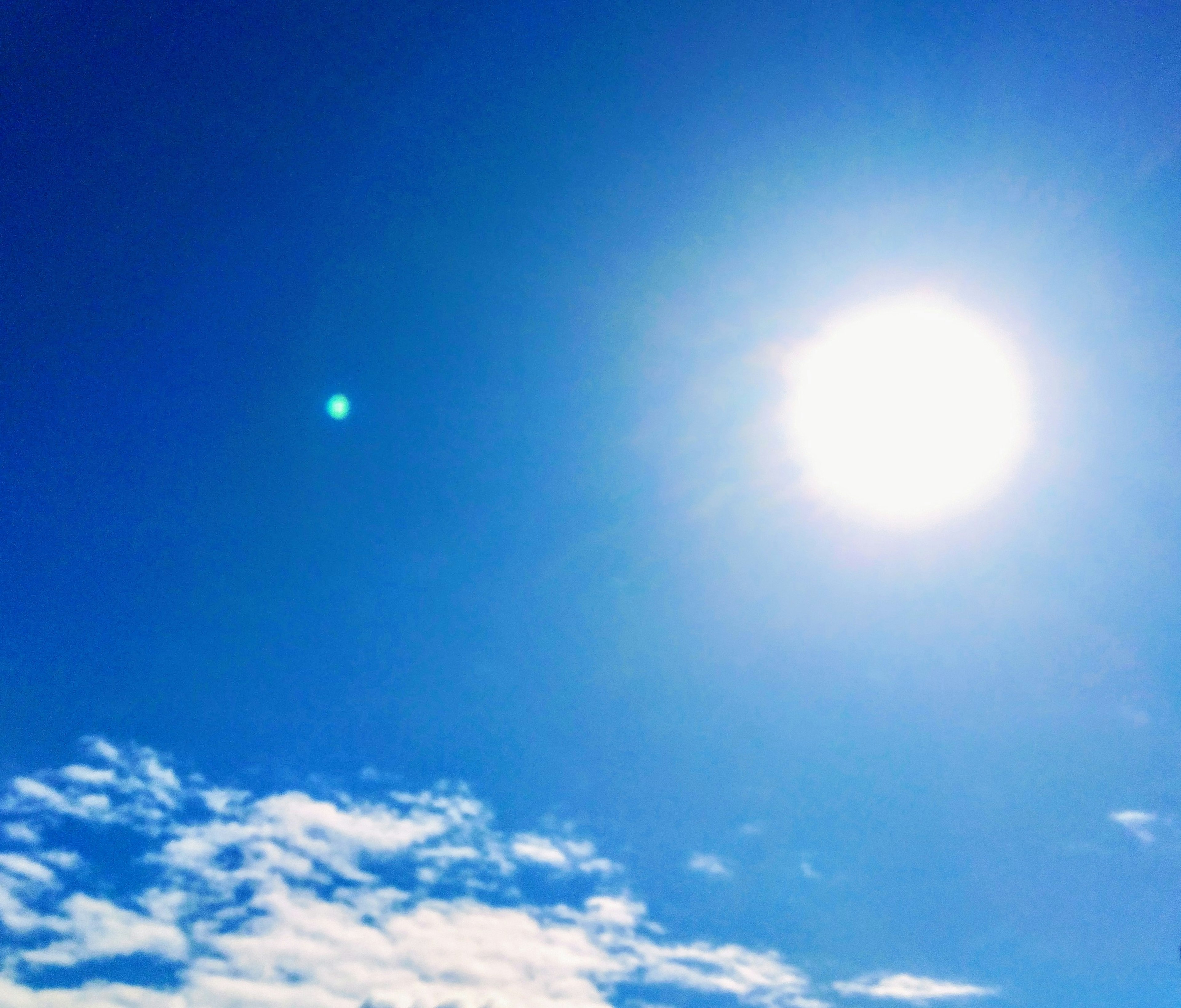 Sole luminoso in un cielo blu chiaro con nuvole bianche