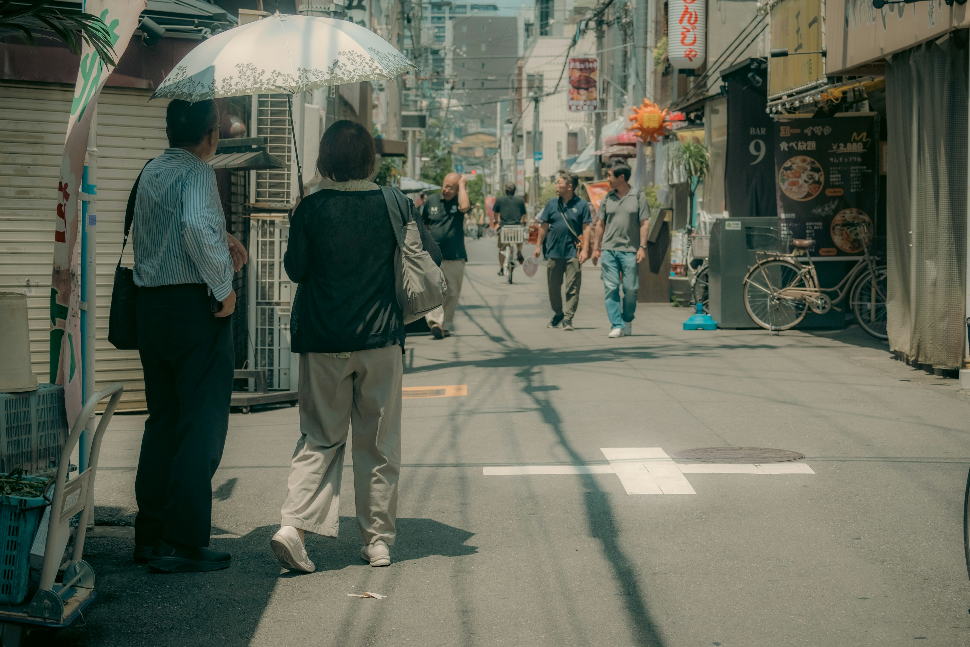 우산을 쓴 남성과 여성이 사람들이 오가는 번화한 거리에서 서 있다